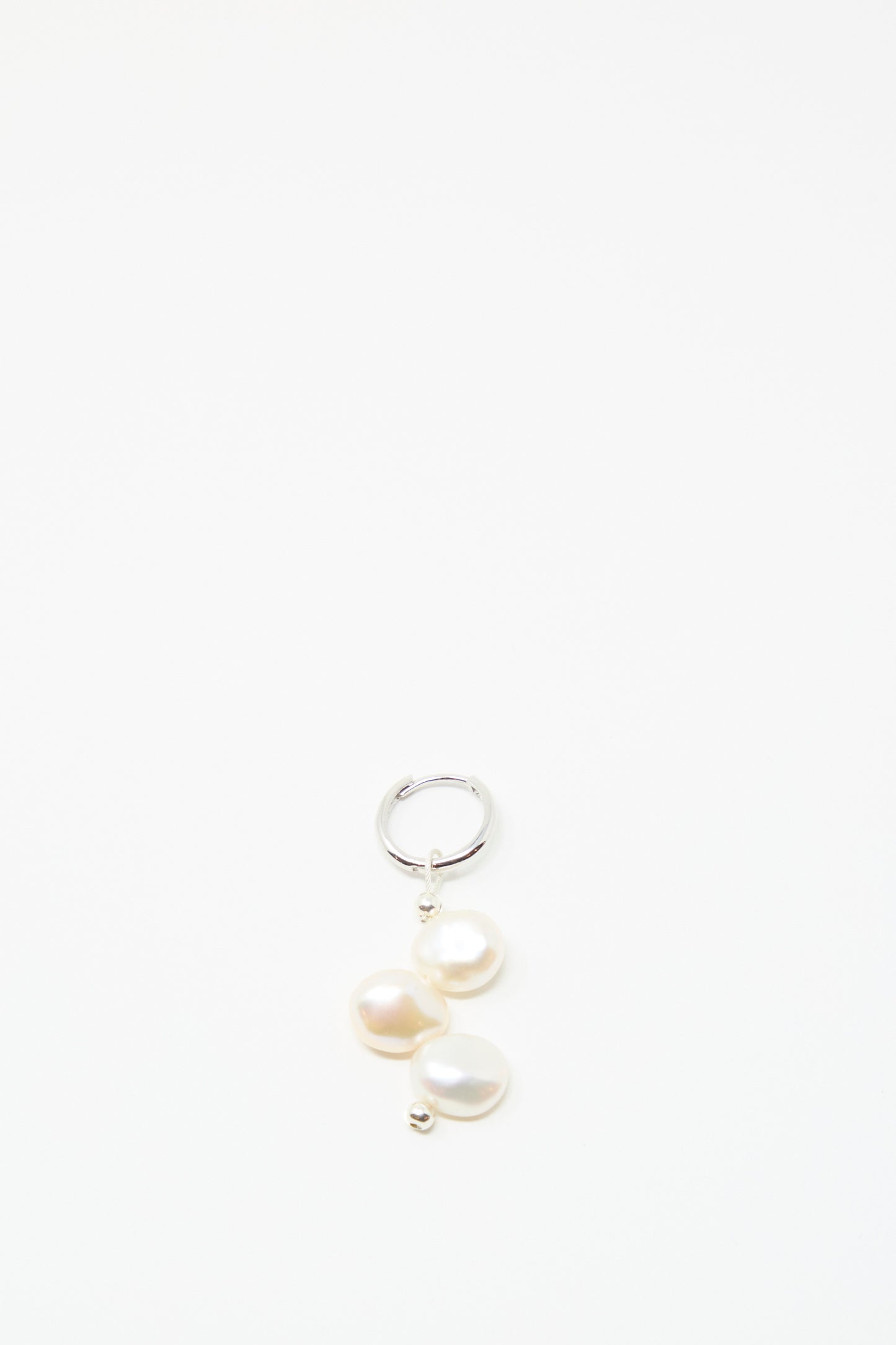 The Santangelo Baba Earring in Triple Baby, a sterling silver hoop featuring three elegant freshwater keshi pearls, is displayed against a plain white background.