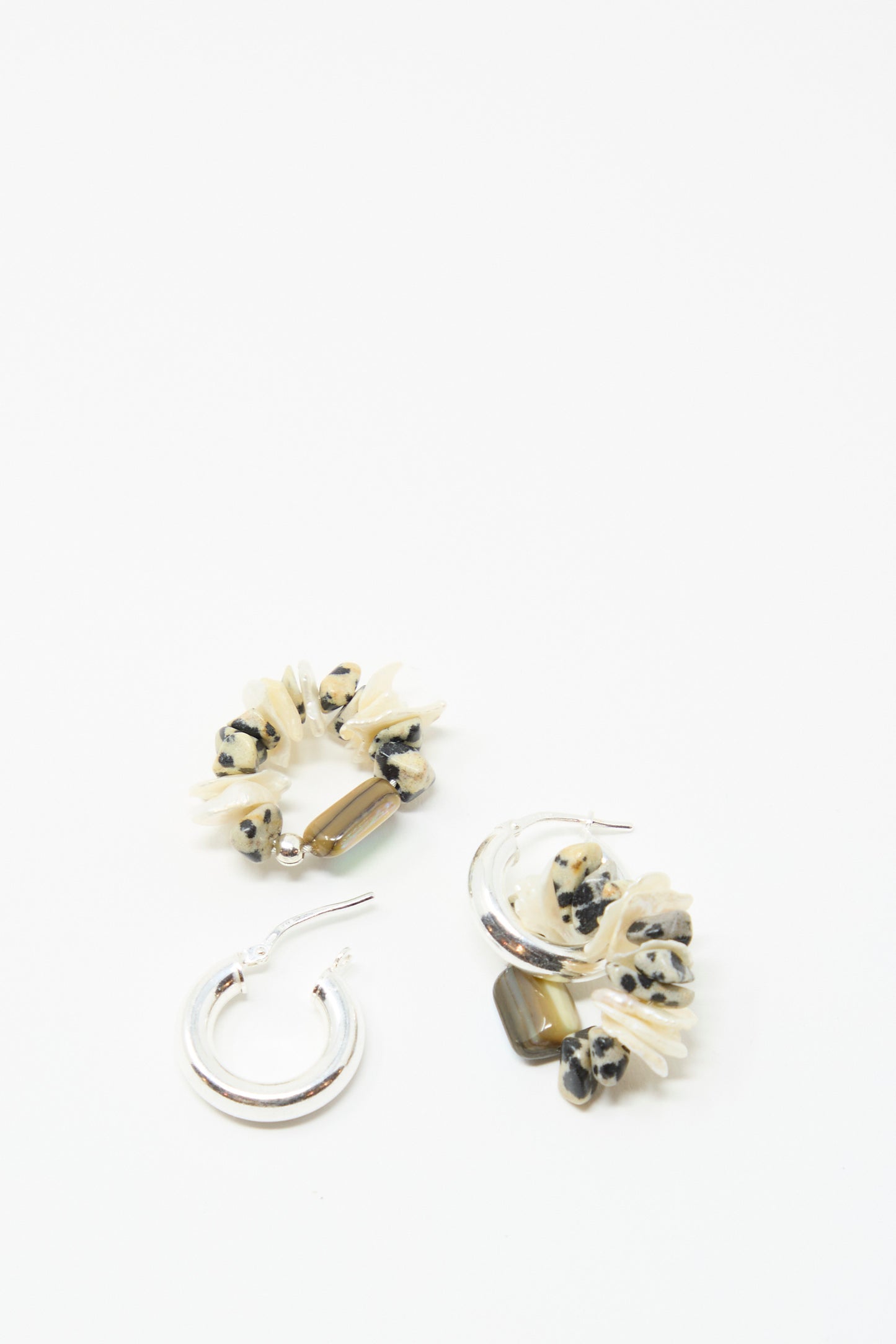 Three Santangelo Che Bomba Earrings in Abalone Hoop—two featuring Dalmatian Jasper beads with brown rectangular accents, and one plain—are arranged on a white background.