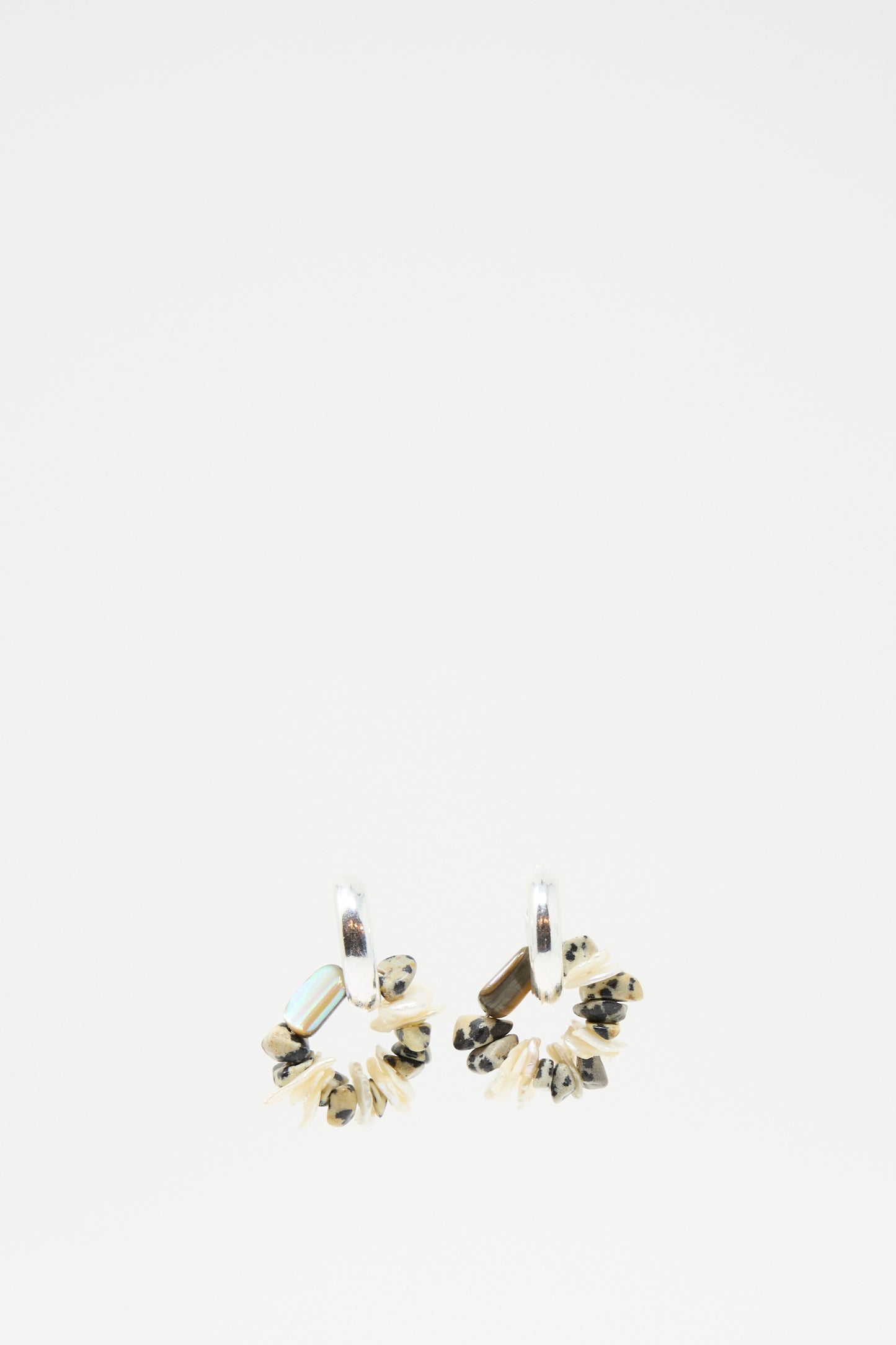 The Santangelo Che Bomba Earrings in Abalone Hoop feature sterling silver hoops adorned with small, irregular black, beige, and turquoise beads and Dalmatian Jasper accents, shown against a plain white background.