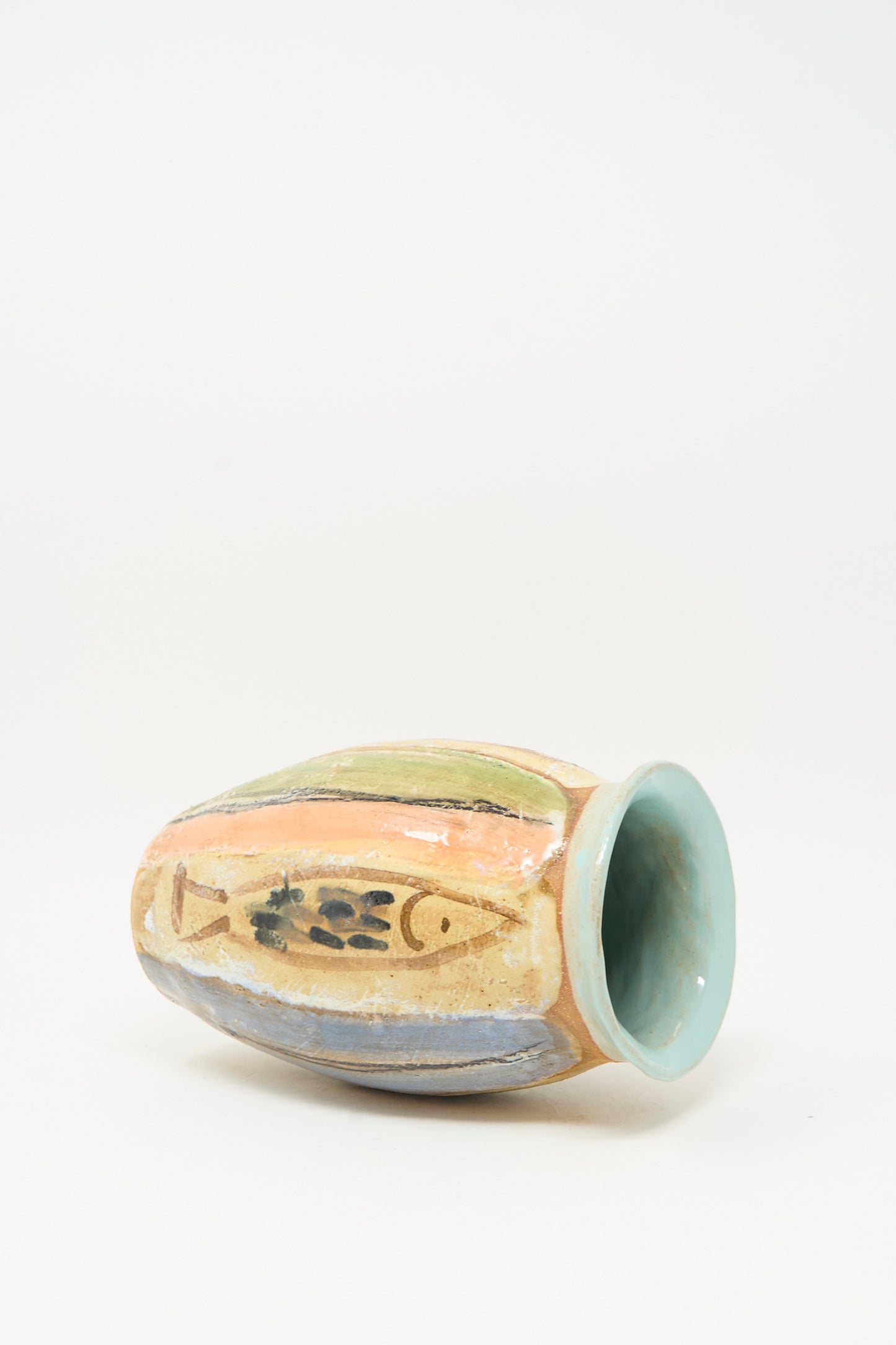 The Fish Vase in Multi Stripe by Shino Takeda is a handmade clay vase with a wide opening, pastel abstract stripes, black markings, and a distinctive fish design on its surface.