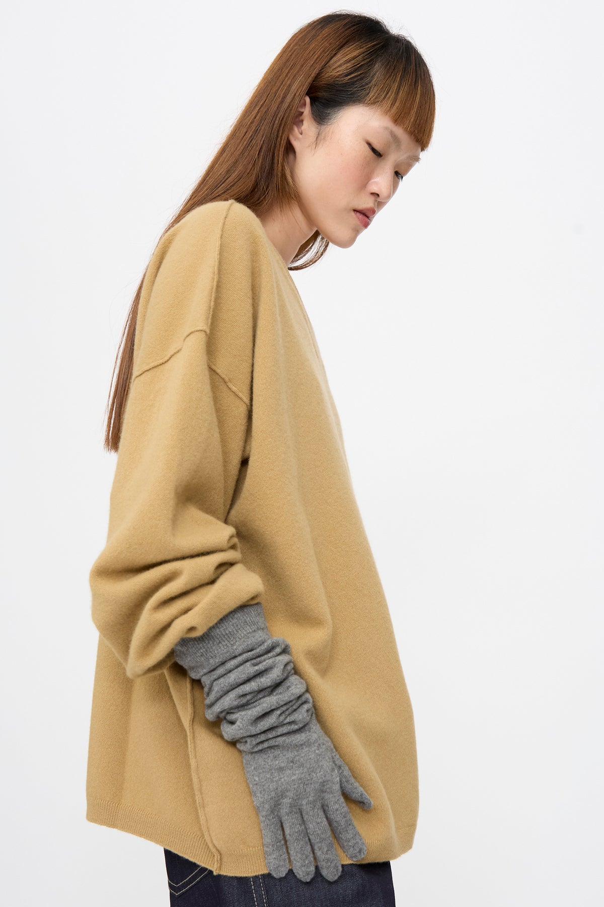 A person wearing a tan long-sleeved top and grey Cashmere Knit Alta Gloves in Metal Melange, worn scrunched on the forearm.
