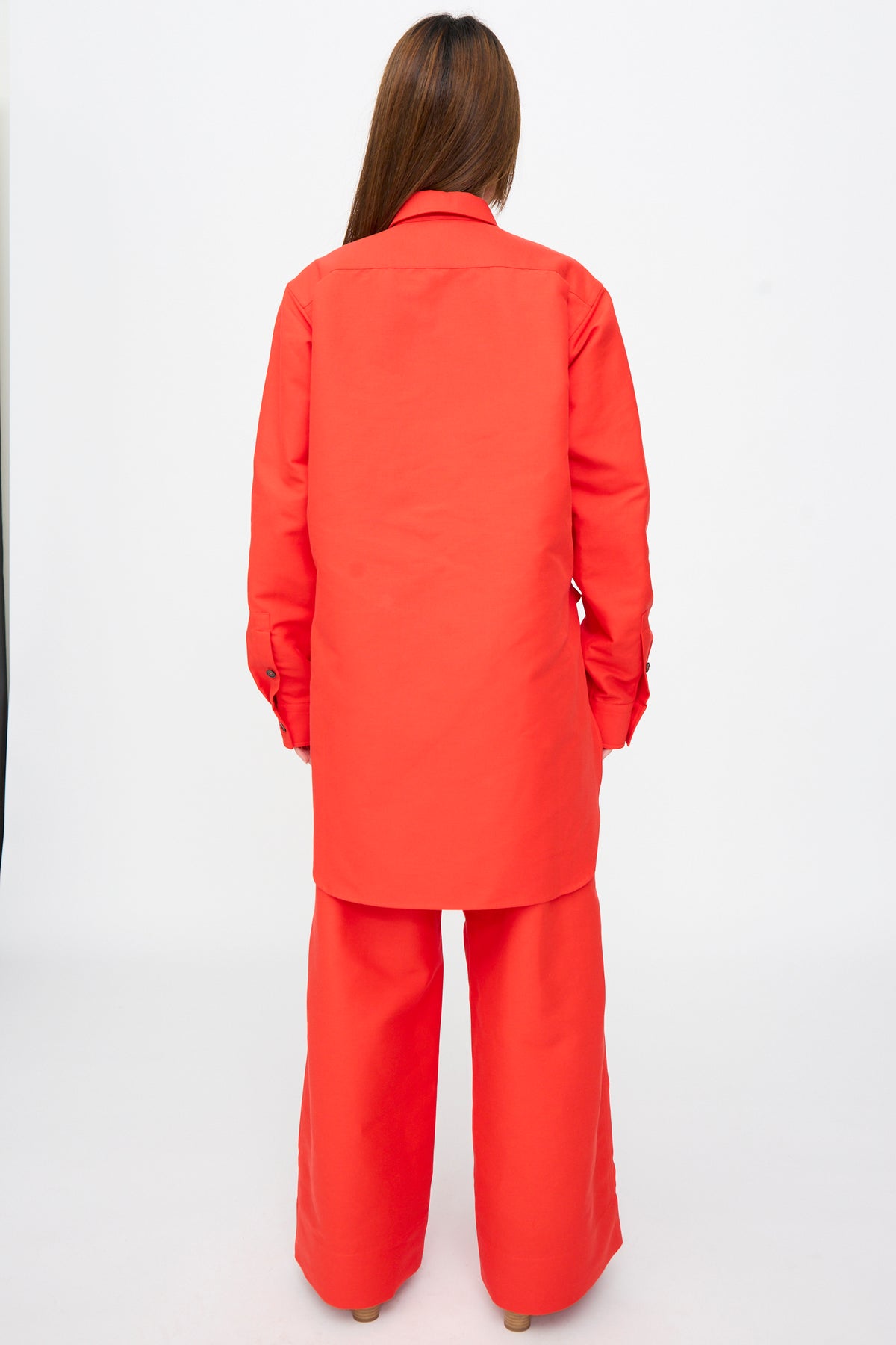 A person seen from behind wearing an oversized Cotton Duchesse Brant Shirt in Fire and matching red wide-leg trousers.