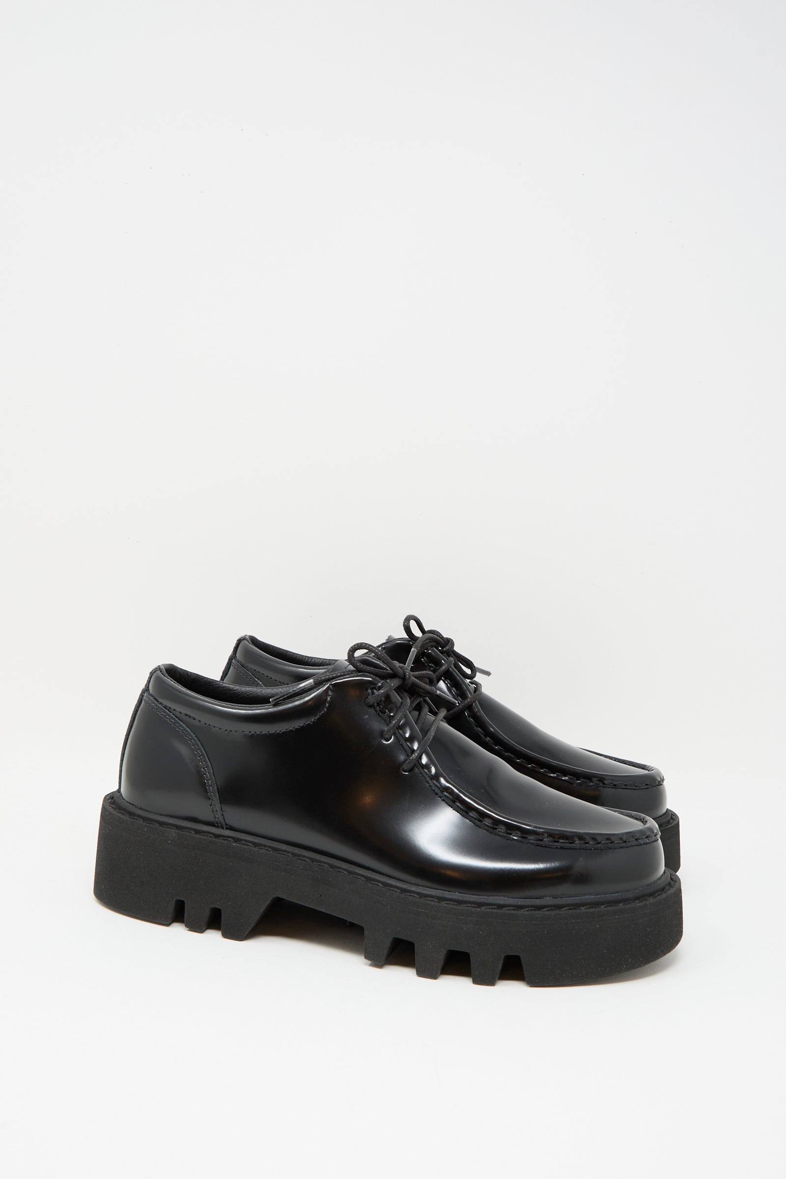 The Sofie D'Hoore Leather Falcone Wallabee Shoe in Black features shiny patent leather, lace-up design, and thick chunky rubber soles, showcased against a plain white background.