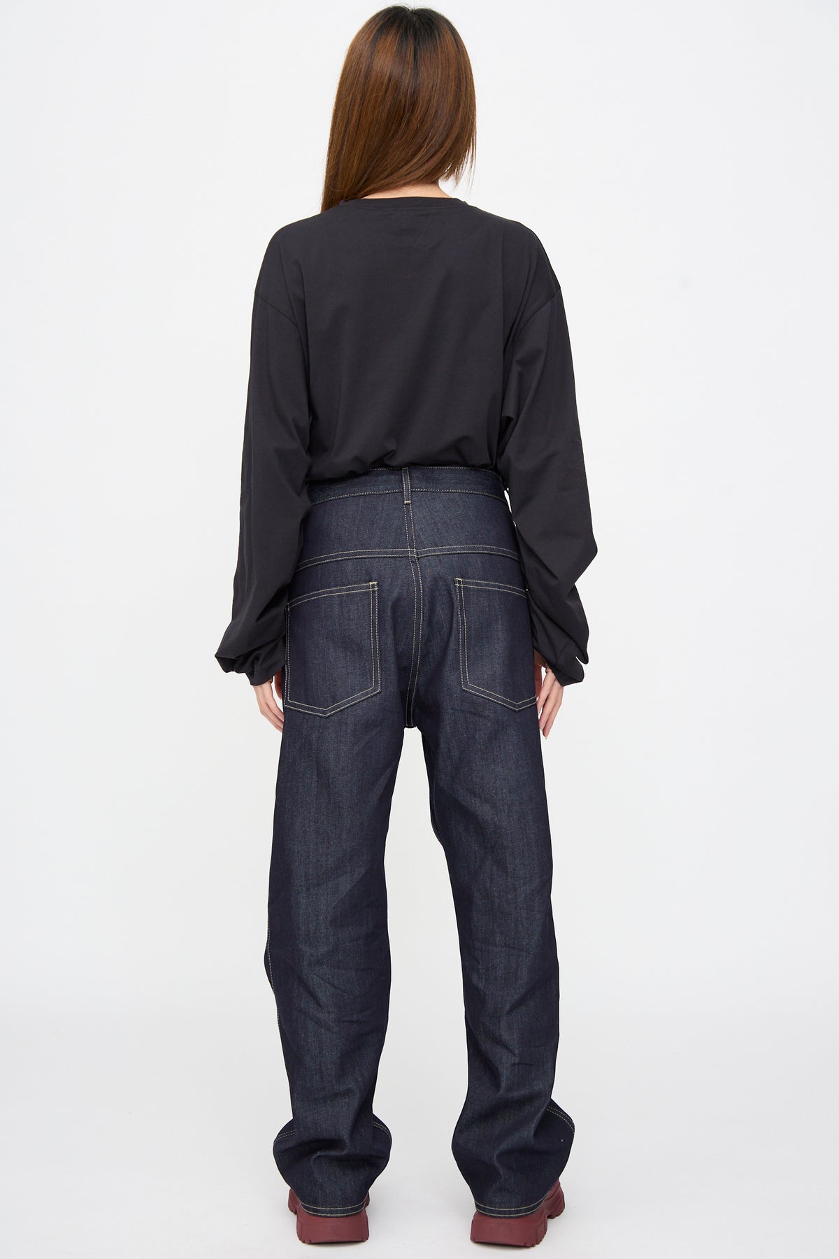 Back view of a person wearing a black long-sleeved shirt and the Sofie D’Hoore Raw Denim Phill Pant in Midnight, featuring contrast stitching, two back pockets, and a relaxed, drop-crotch fit.
