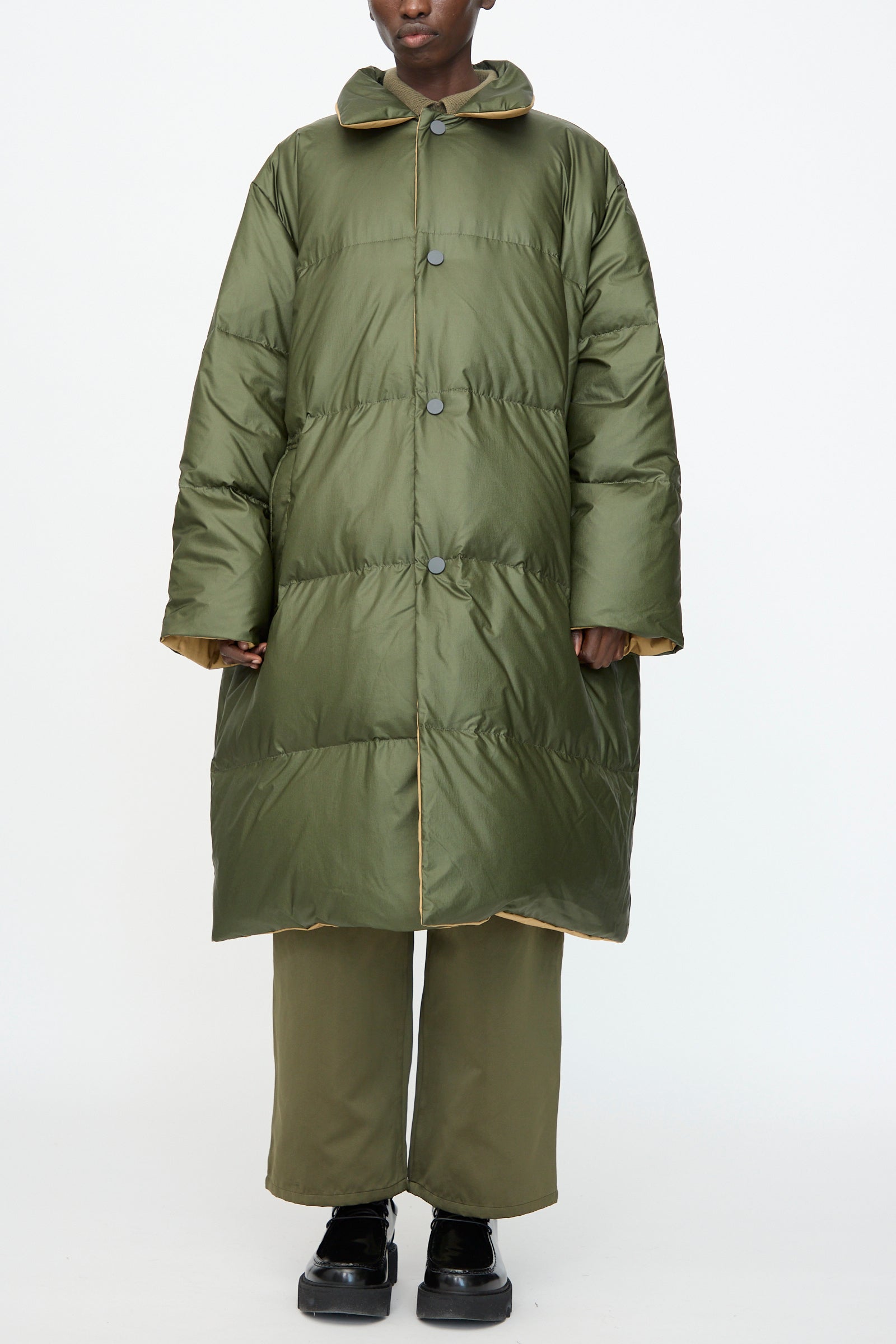 Model wears the Sofie D'Hoore Reversible Otis Down Coat in Mushroom and Khaki with matching pants and black platform shoes, standing against a plain white background.