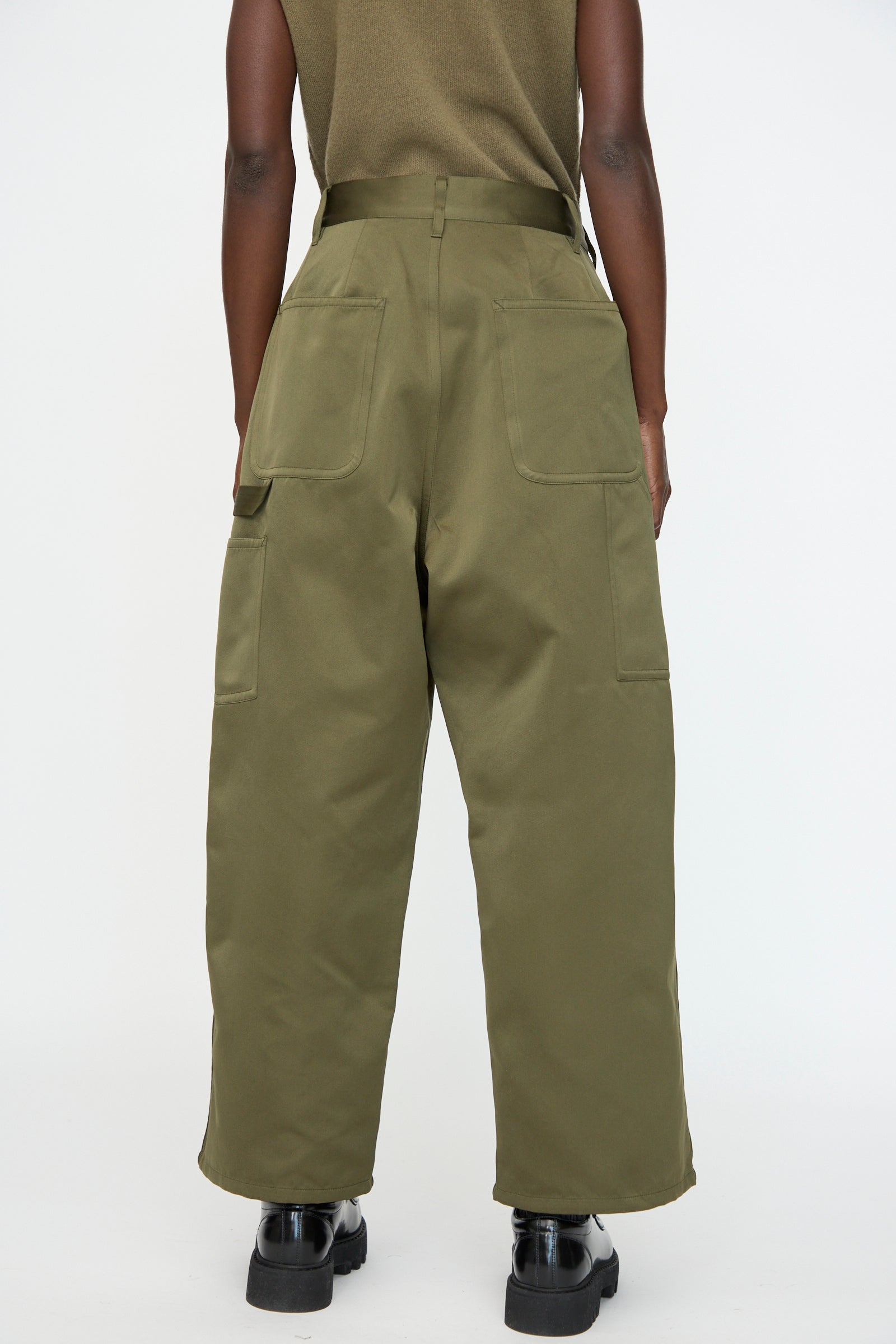 Person wearing Sofie D’Hoore Satin Polke Pant in Laurel, featuring an oversized fit and large back pockets, with black shoes, photographed from behind against a plain white background.