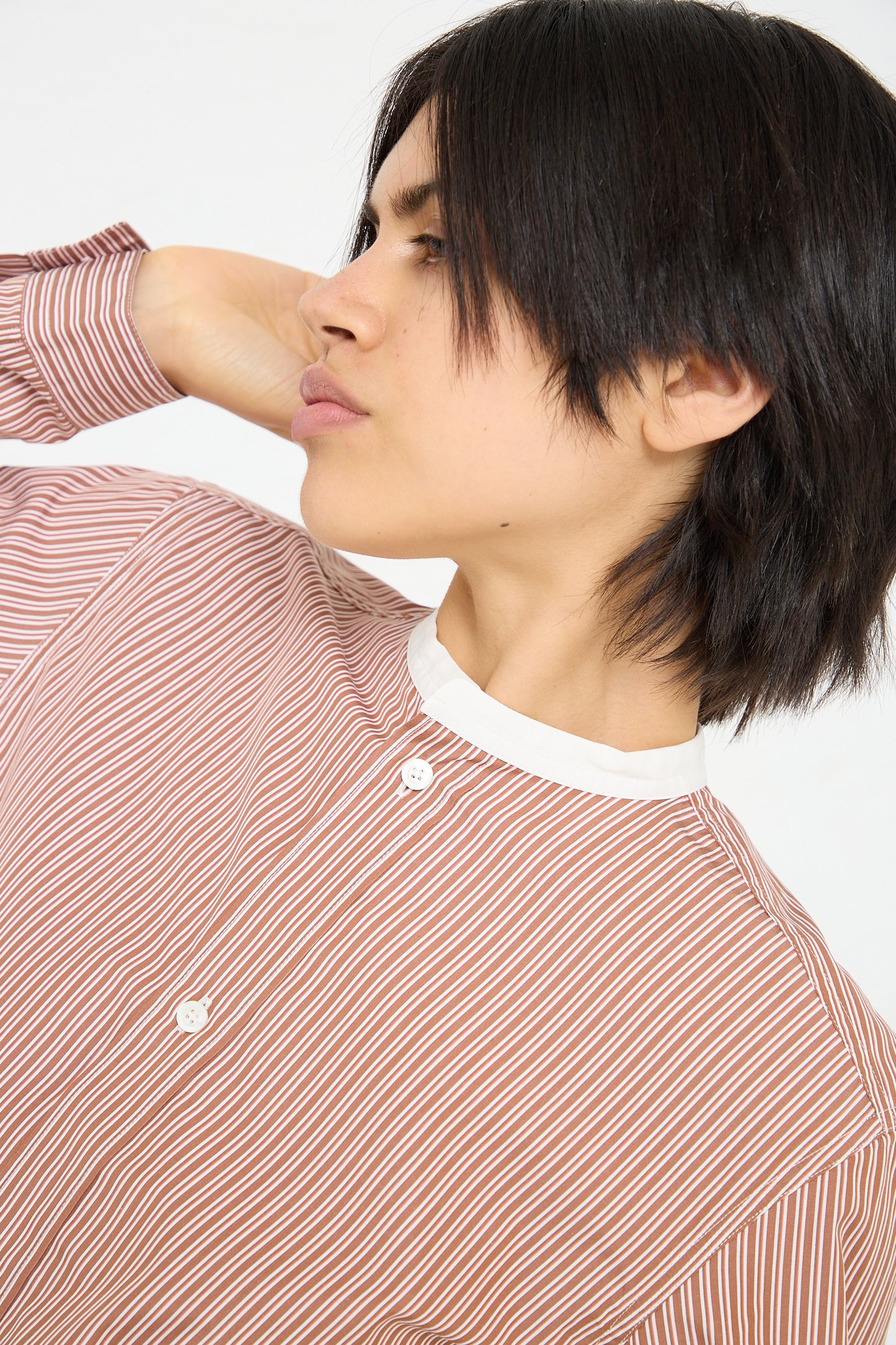 A woman wearing a Sofie D'Hoore Woven Cotton Boyd Shirt in Brick Stripe and Ivory, demonstrating a sustainable approach.