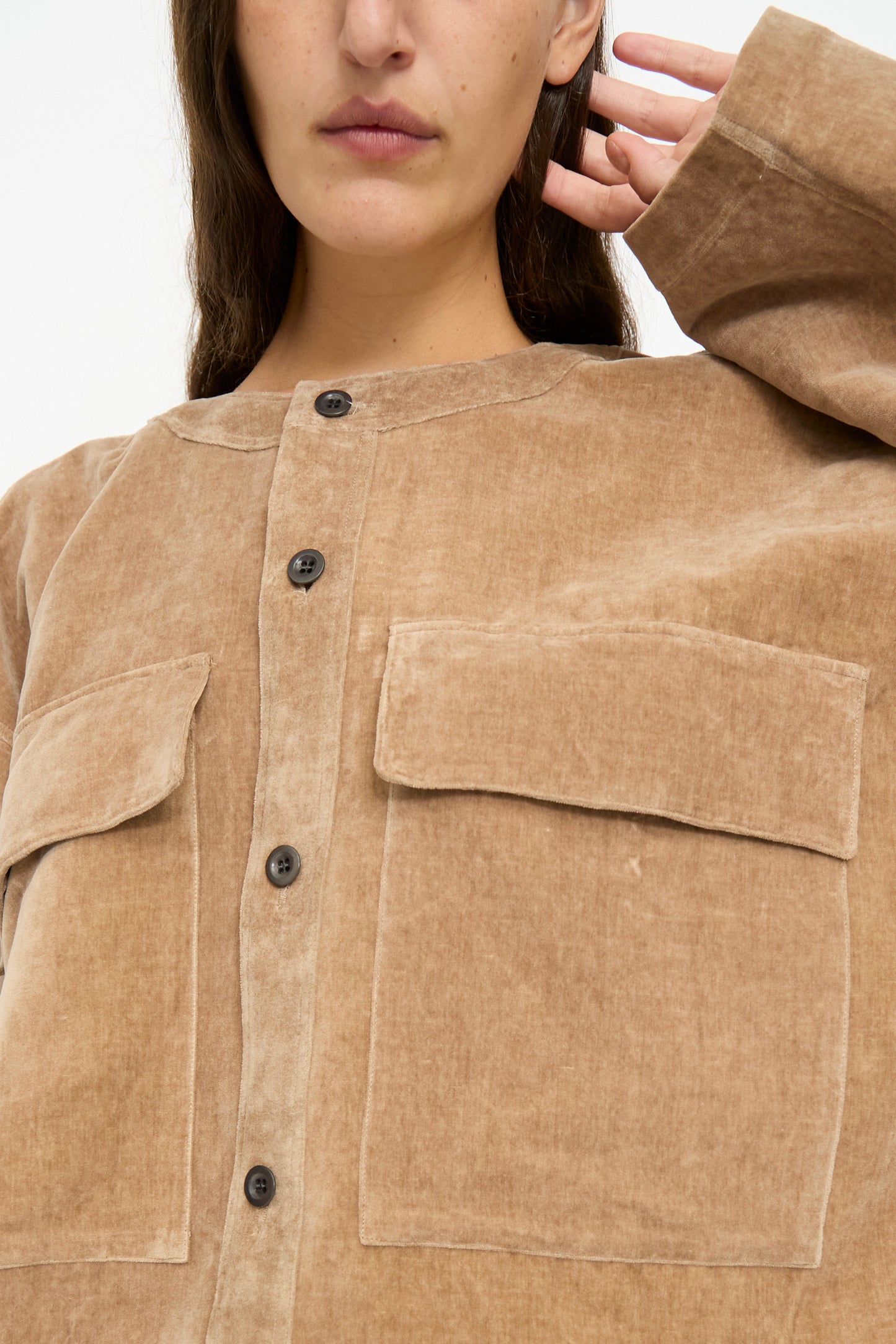 A person wearing the SONO Sid Shirt in Desert Rose—a relaxed fit, light brown button-down with large front pockets, crafted from organic cotton linen—shown from the shoulders down, face not visible.
