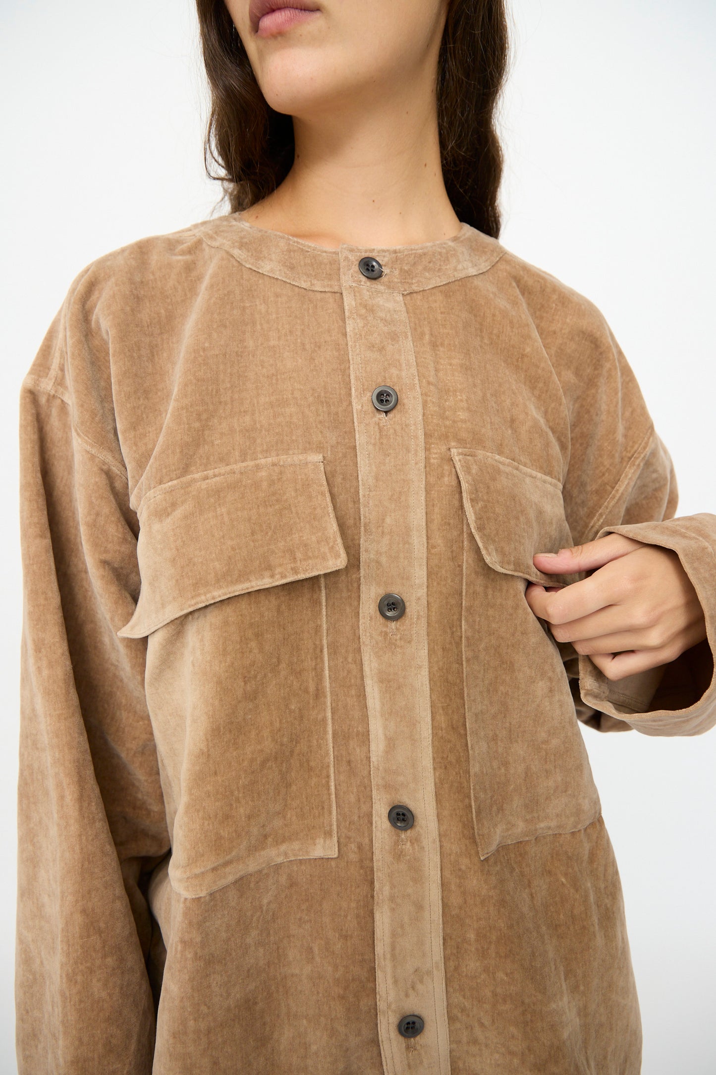 A person wearing the SONO Sid Shirt in Desert Rose, a relaxed fit button-down with large front pockets, holding one side of the shirt near the buttons.