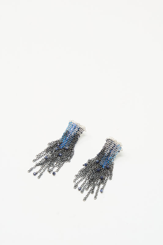 Stephanie Schneider’s Sterling Silver and Silk Earrings in Blue with Sapphires feature black and blue chain fringe cascading from a small white base, displayed on a plain white background.