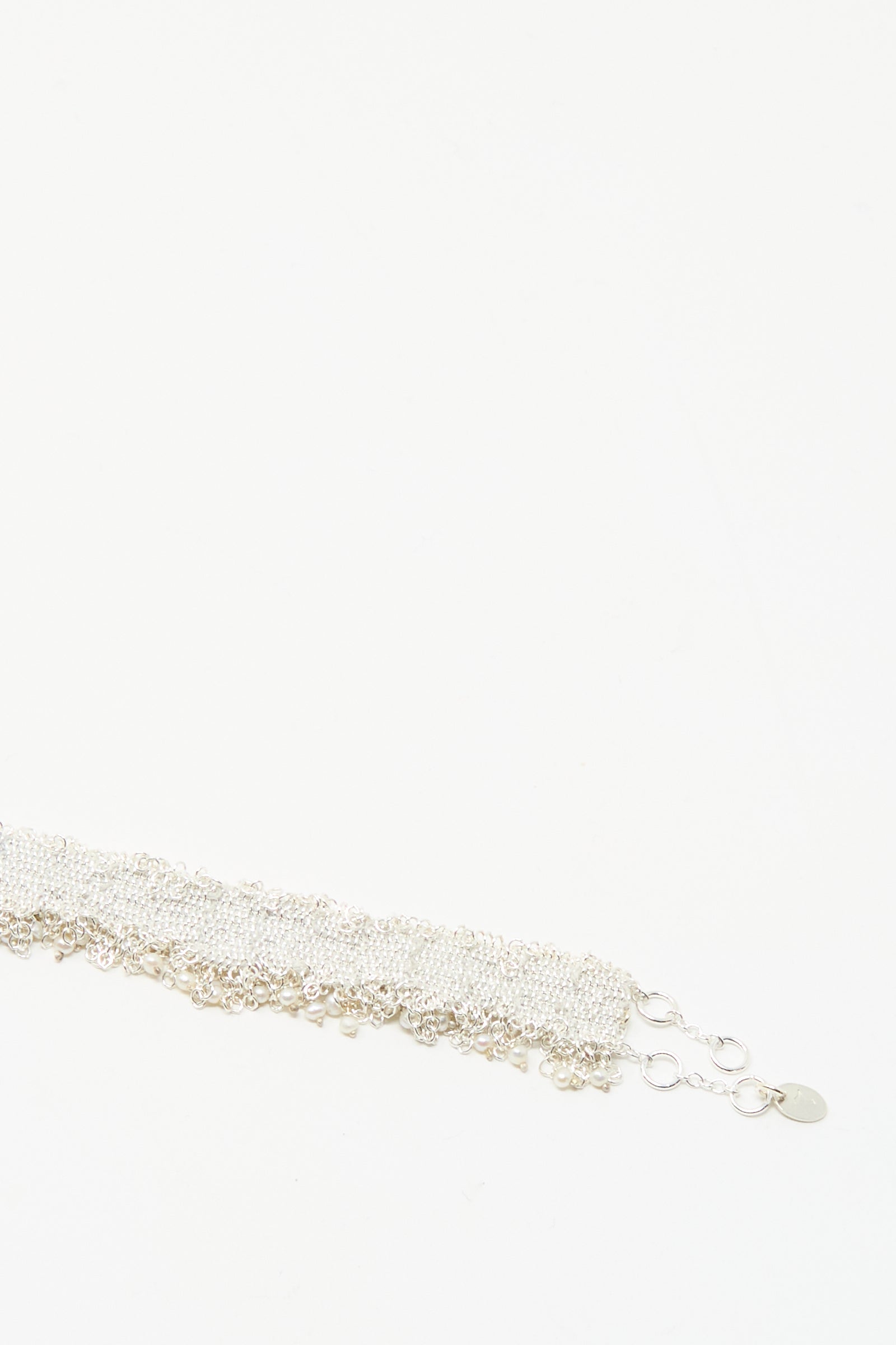 The Stephanie Schneider Silver and Silk Woven Bracelet with Pearls features multiple linked strands and a clasp, displayed against a plain white background.