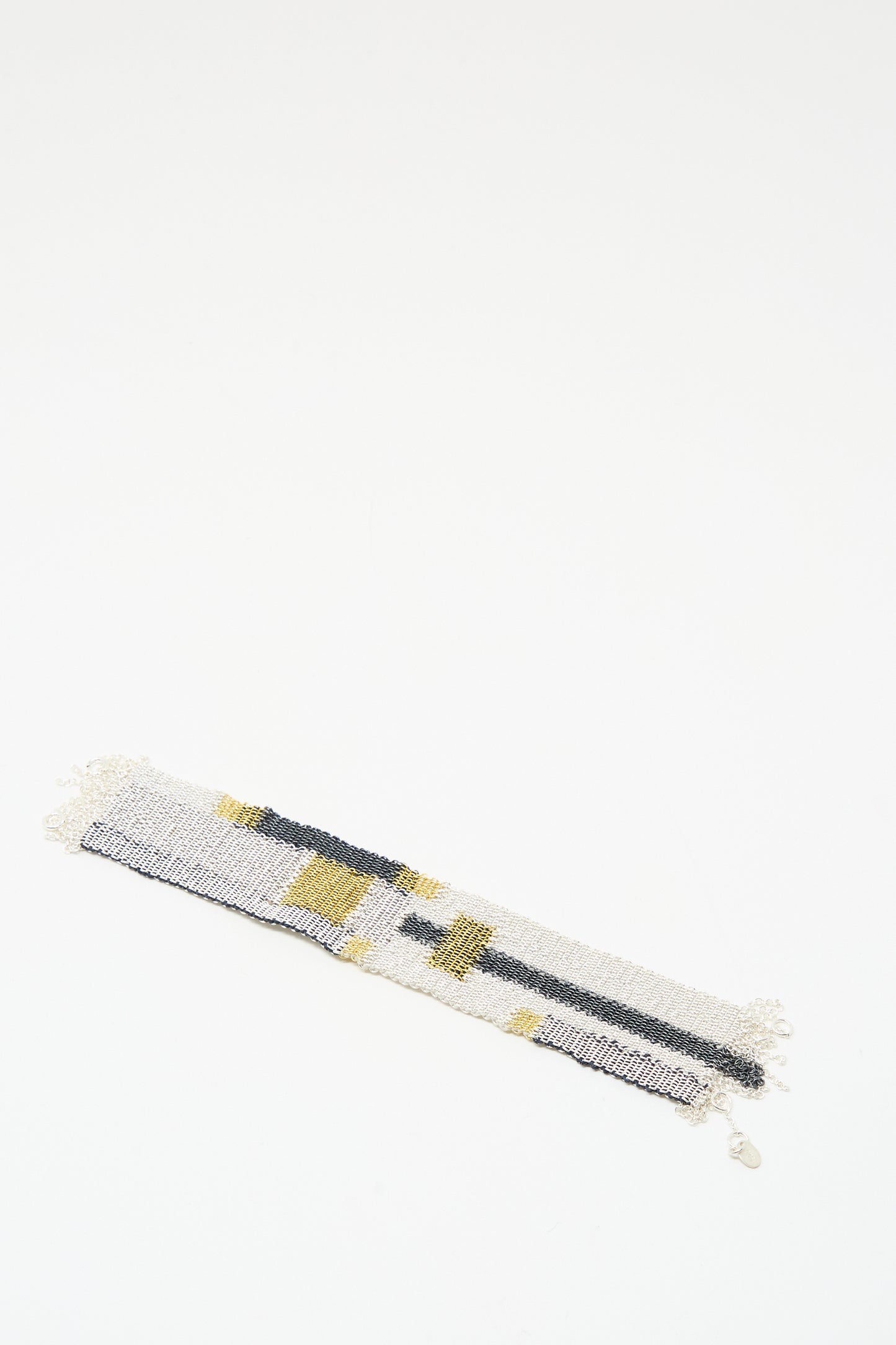 The Stephanie Schneider Silver Oxidized, Gold Plated and Silk Woven Bracelet with geometric gray, white, and yellow patterns is displayed on a white background.
