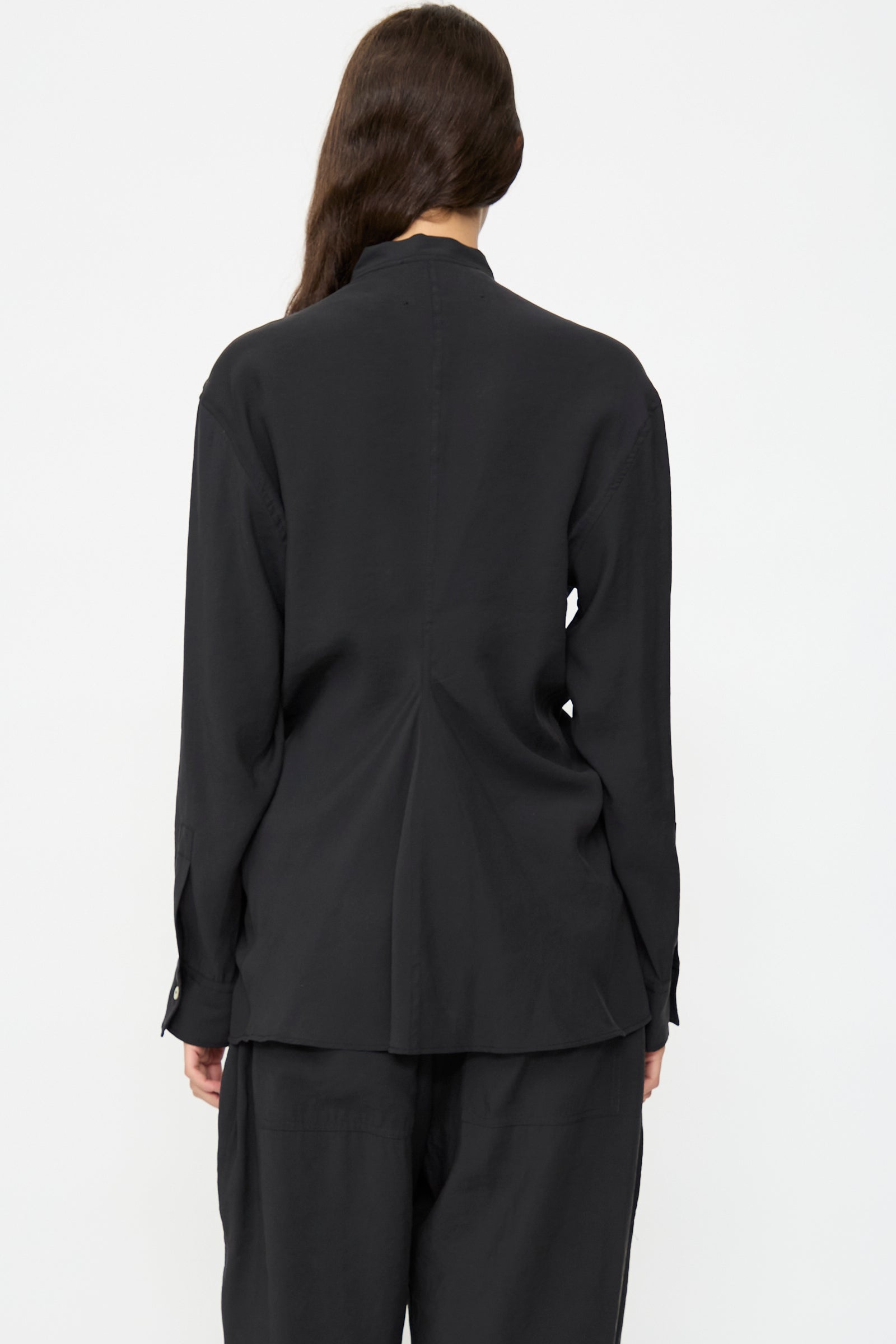 A person stands with their back to the camera, wearing the Studio Nicholson Acre Top in Darkest Navy and matching pants, set against a plain white background.