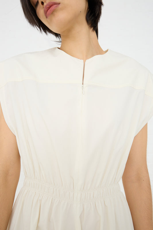 Woman wearing a Studio Nicholson Katrine Ruched Waist Dress in Parchment with a zipper detail on the back.