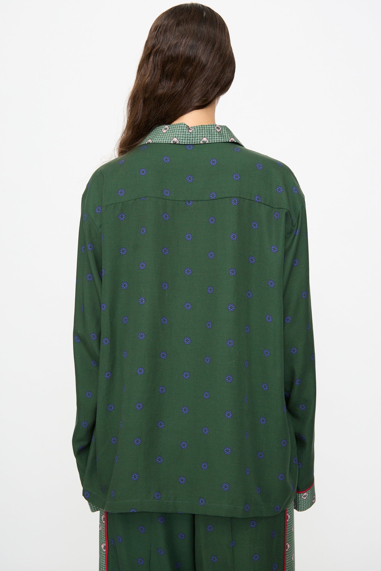 A person with long brown hair, seen from the back against a plain background, wears the TOGA ARCHIVES Inner Print Long Sleeve Shirt in Green—a loose-fitting top featuring blue dots and a plaid collar.