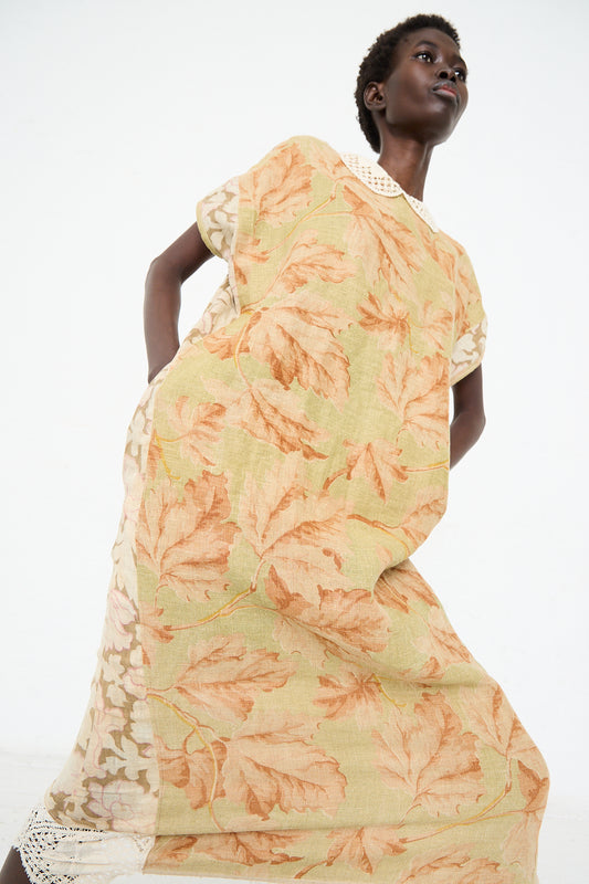 Person wearing a beige and orange leaf-patterned dress that looks like an Antique French Floral Caftan by Thank You Have A Good Day, standing against a plain white background.