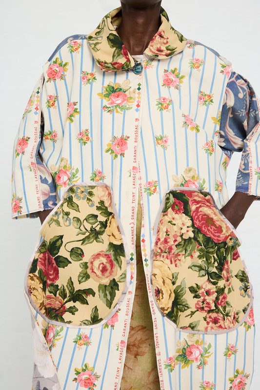 A person is wearing a Thank You Have A Good Day Antique French Floral Duster. The duster features striped material with large floral-patterned pockets and is crafted from cotton/linen. It has a button closure at the front and a wide collar.