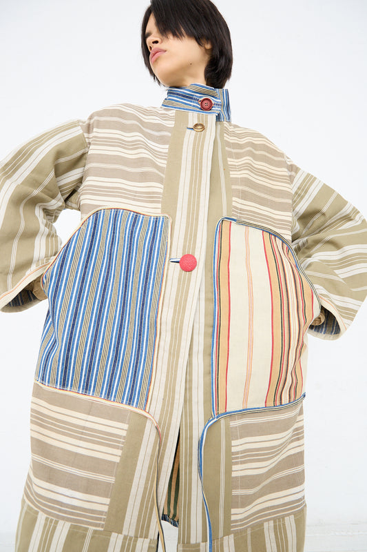 A person modeling a Patchwork French Ticking Fishtail Parka by Thank You Have A Good Day, featuring vintage cottons with a mix of vertical and horizontal patterns, standing against a white background.