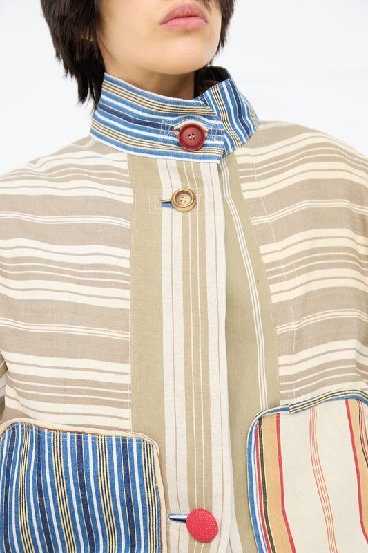A close-up of a person wearing a Thank You Have A Good Day Patchwork French Ticking Fishtail Parka with contrasting collar and pocket details, featuring a variety of vintage cottons and button accents.