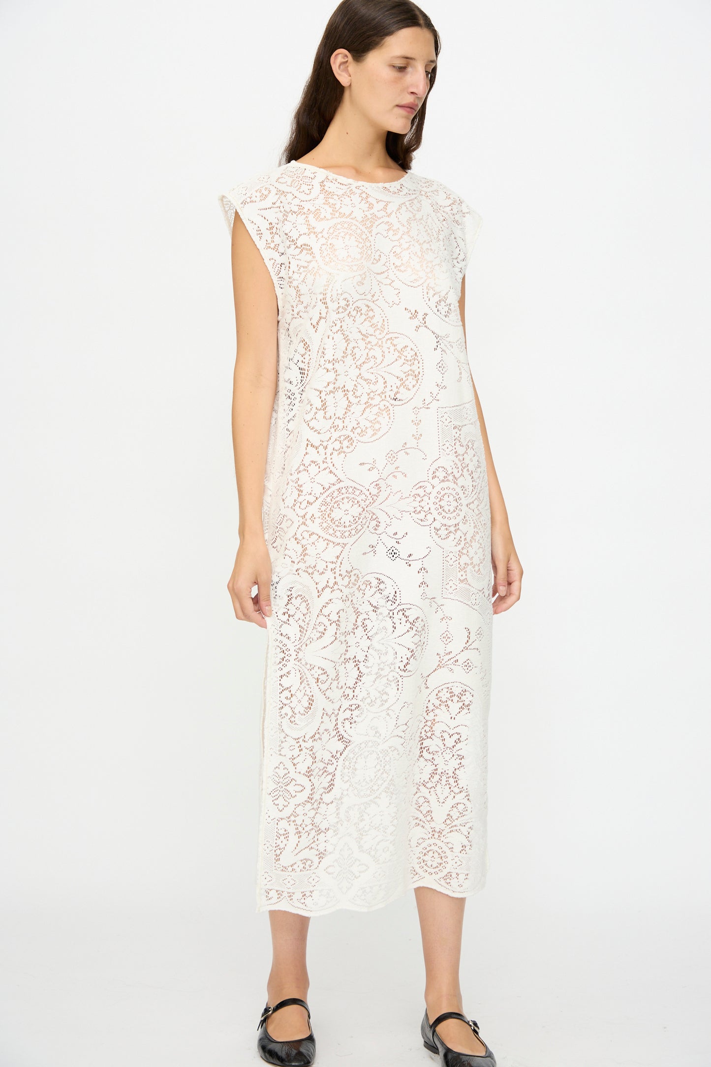 A woman wears the Quaker Lace Caftan by Thank You Have A Good Day—an ankle-length, sleeveless piece made from antique Quaker lace with a floral pattern—paired with black flats. Made in New York.