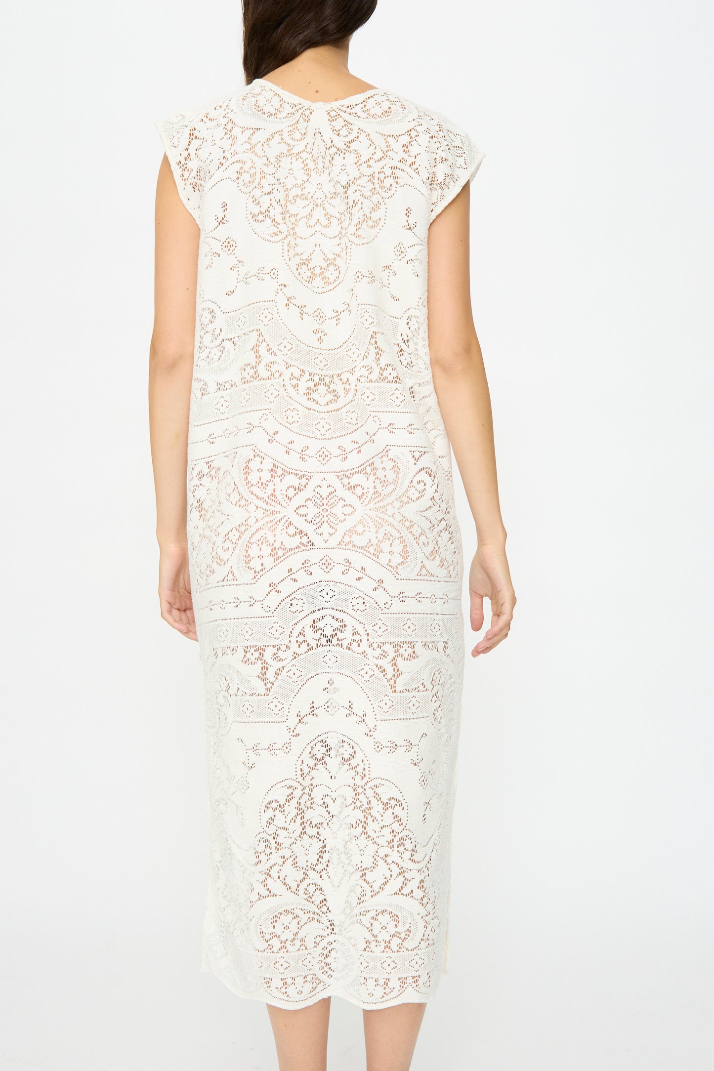 A woman faces away, wearing the Thank You Have A Good Day Quaker Lace Caftan—a white, calf-length dress with intricate antique quaker lace patterns and short sleeves.