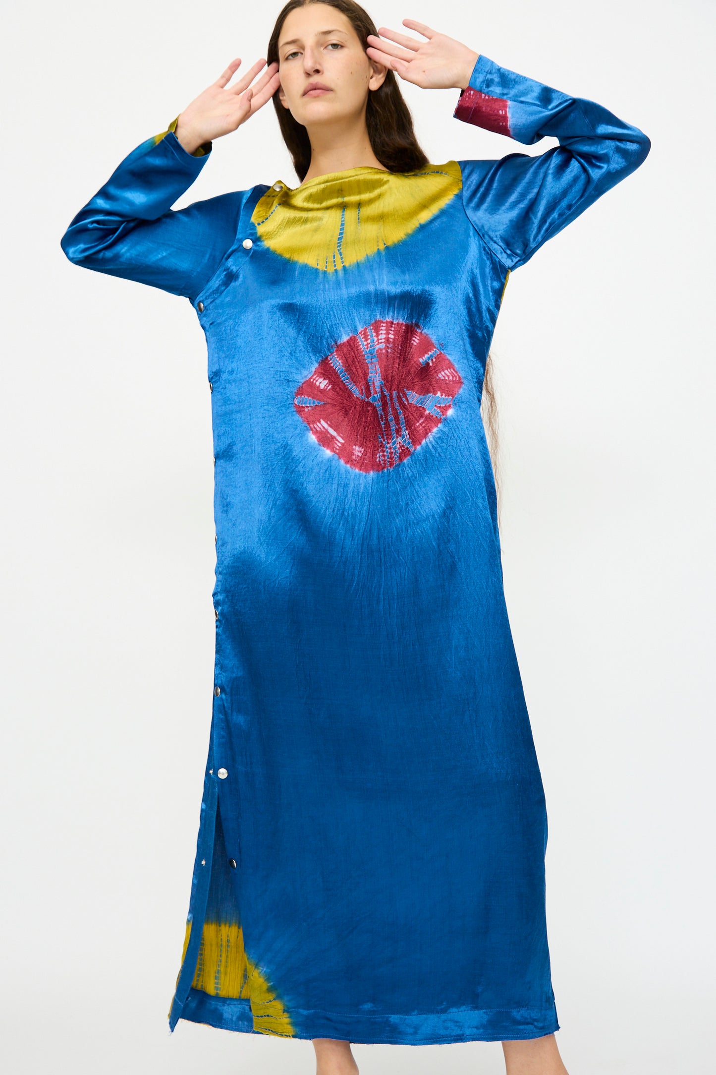 A woman poses in the TIGRA TIGRA Shibori Snap Dress in Jewel Blue, Acid Green, and Magenta, featuring a distinctive Shibori print and crafted in India.