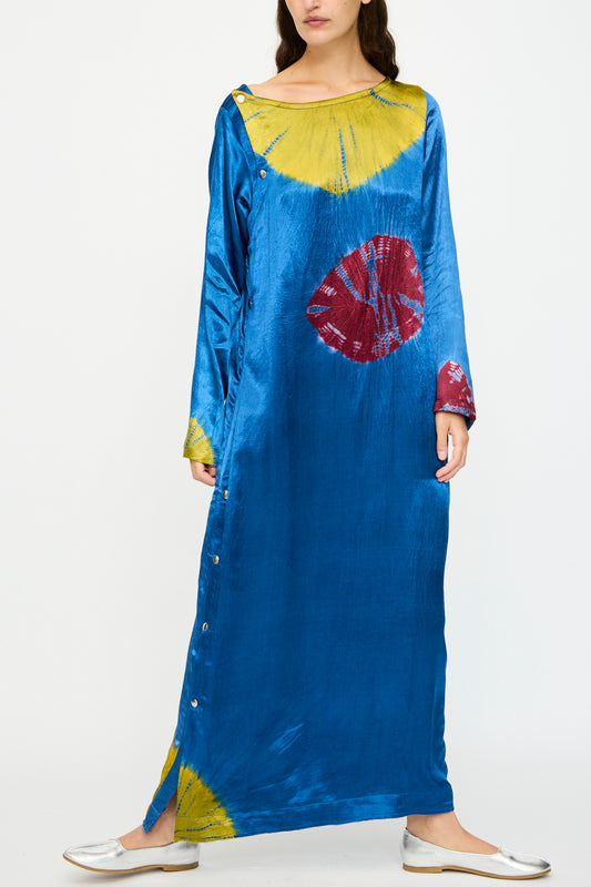 A woman wearing the TIGRA TIGRA Shibori Snap Dress in Jewel Blue, Acid Green, and Magenta with long sleeves, side button details, and silver flats.
