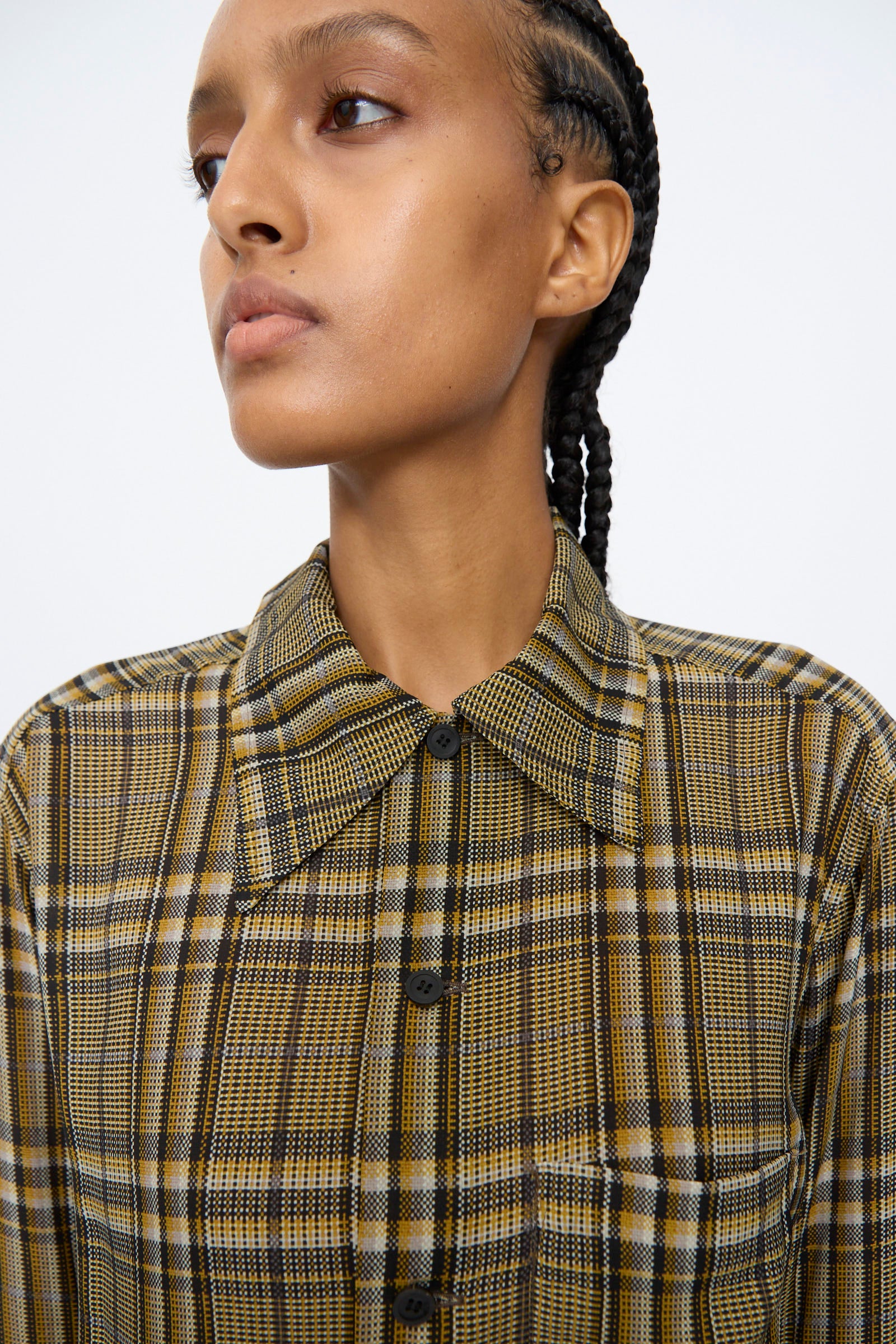 Person wearing the TOGA ARCHIVES Rayon Print Shirt in Brown with hair in tight braids, looking to the side against a plain background.