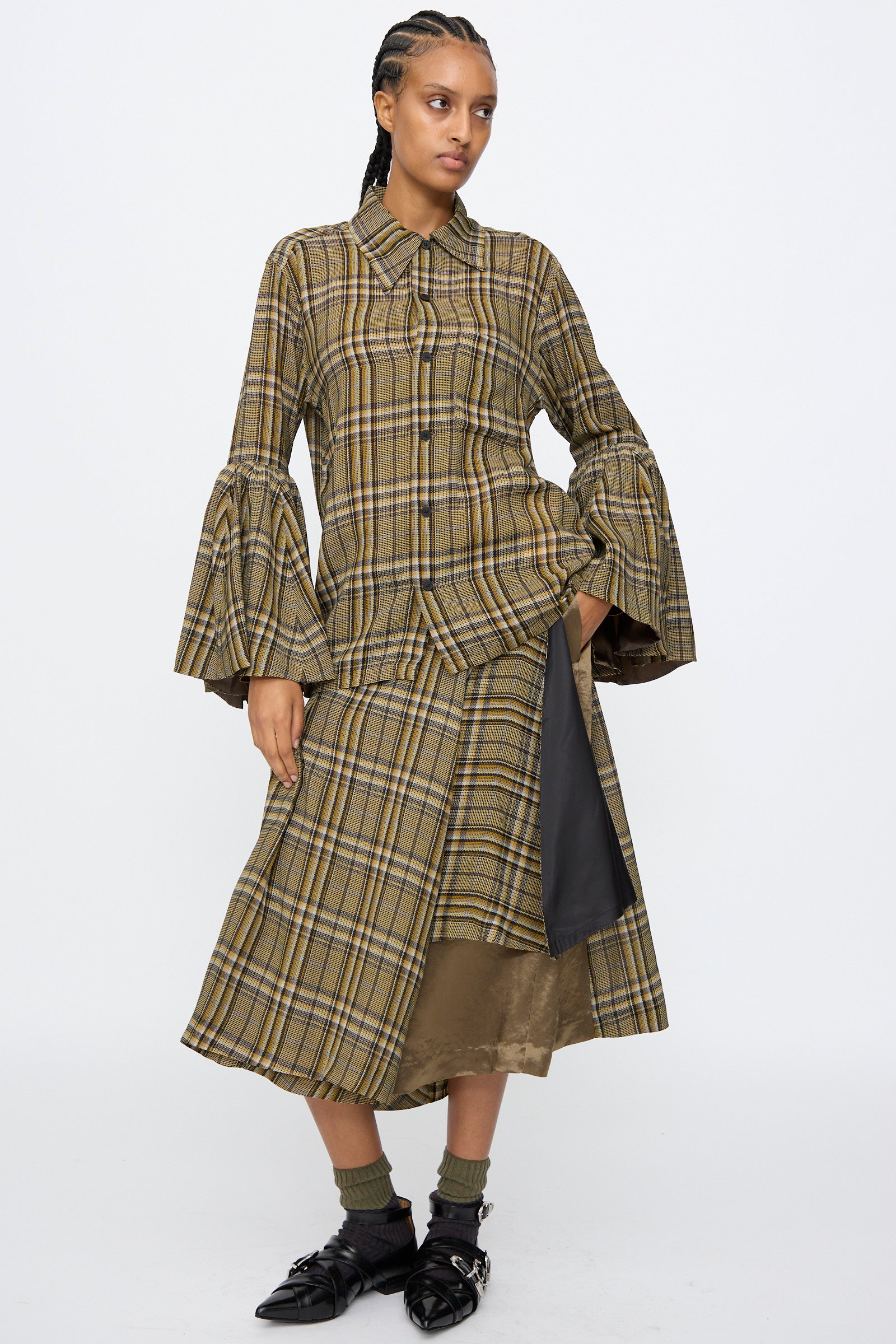 A person wears the TOGA ARCHIVES Rayon Print Shirt in Brown, styled with a matching midi skirt, black pointed shoes, and dark socks, standing against a white background.