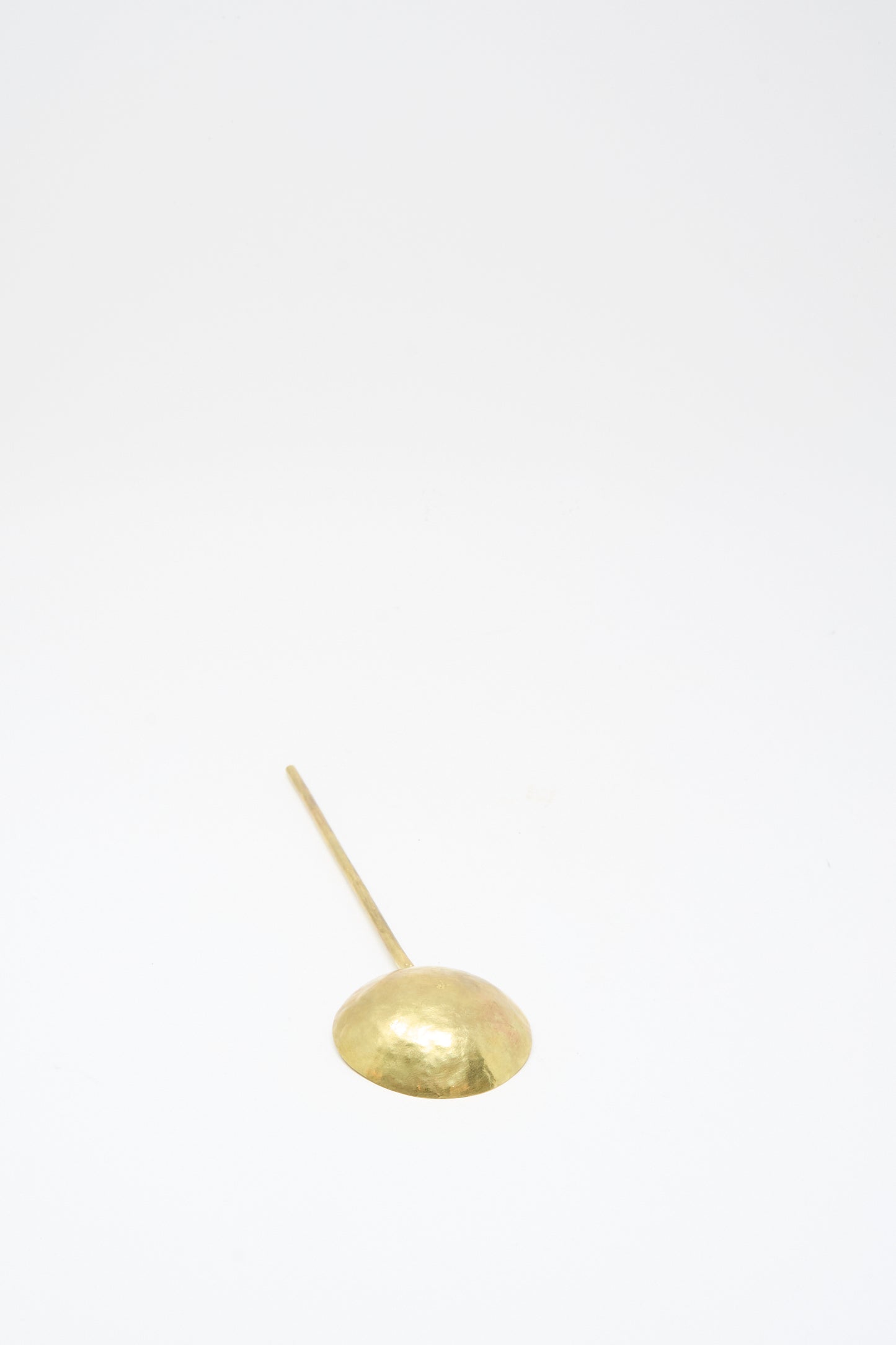 The Totem Home Brass Serving Spoon, featuring a round shallow bowl and long handle, handcrafted in Portugal, is displayed on a plain white background.