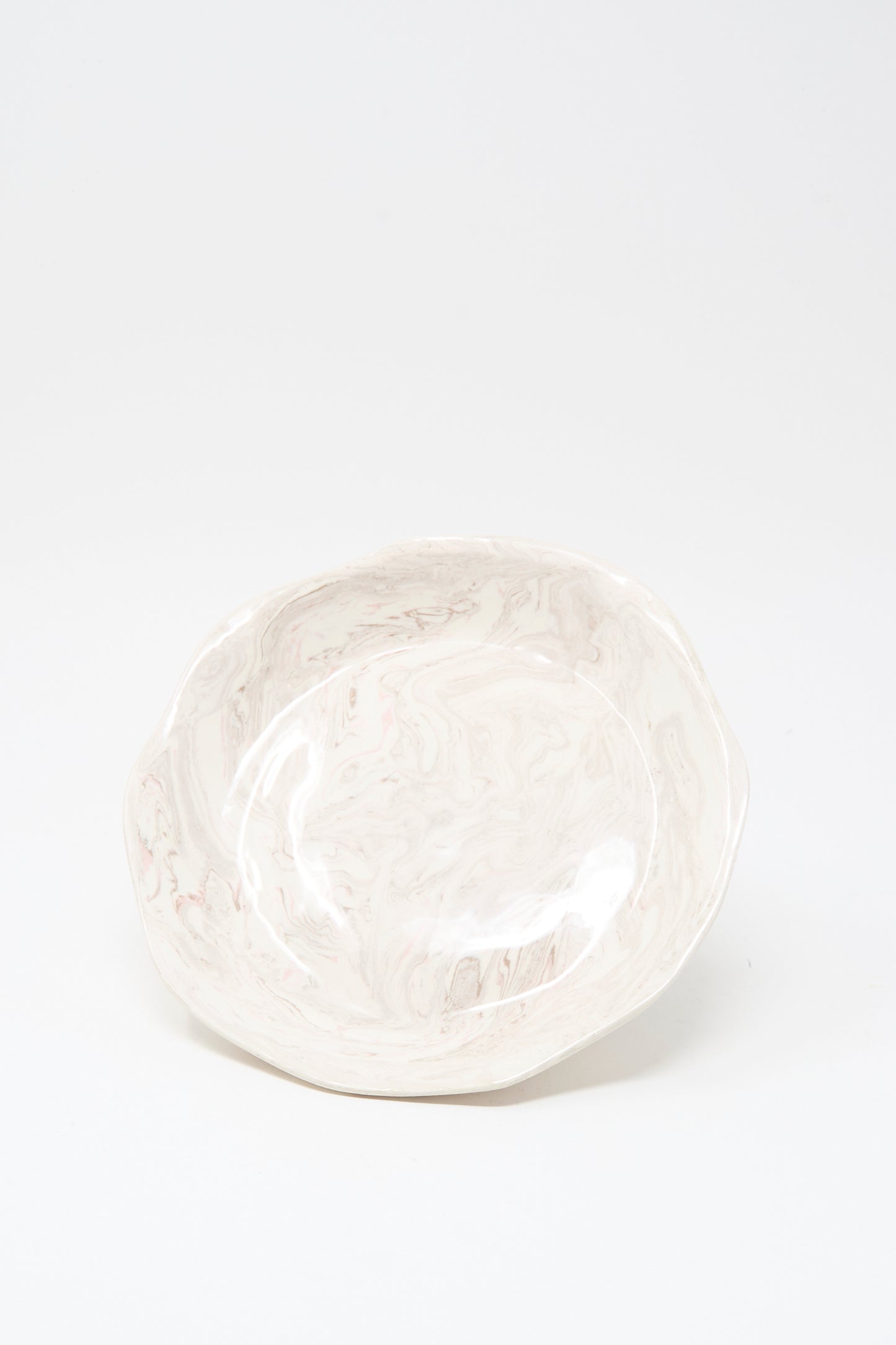 The Wild Rose Shallow Bowl by Totem Home is a handmade ceramic bowl featuring a marbleized pink glaze, crafted in Portugal and shown on a plain white background.