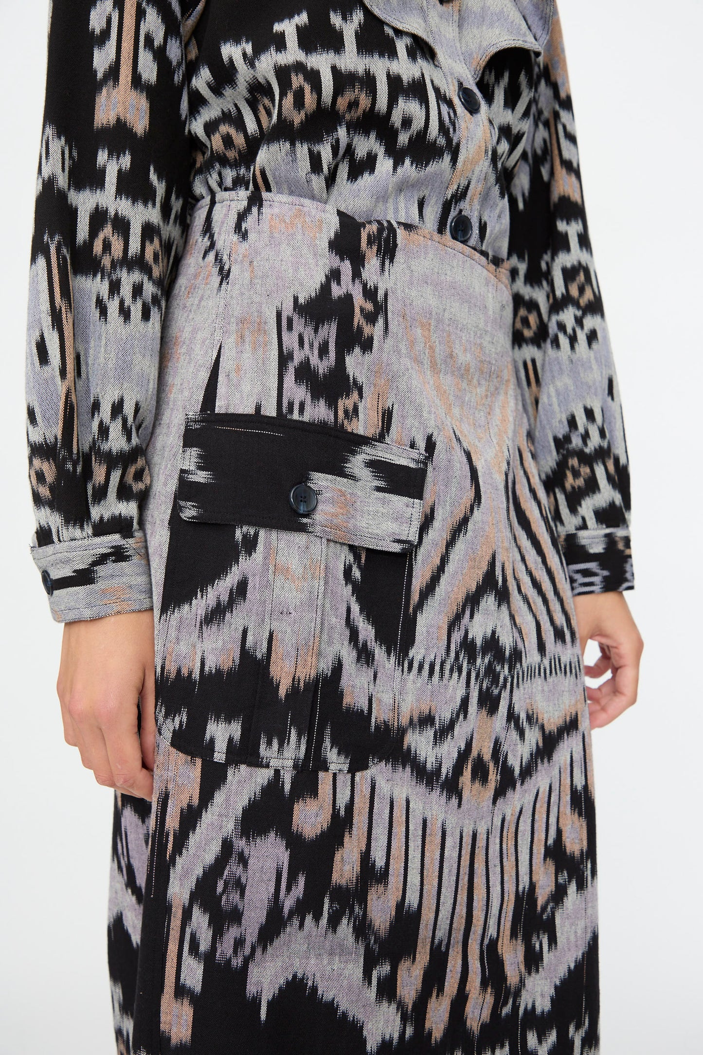 A person wearing the Mila Pencil Skirt in Tigereye by Ulla Johnson, featuring black, gray, and beige abstract patterns and a large buttoned pocket.