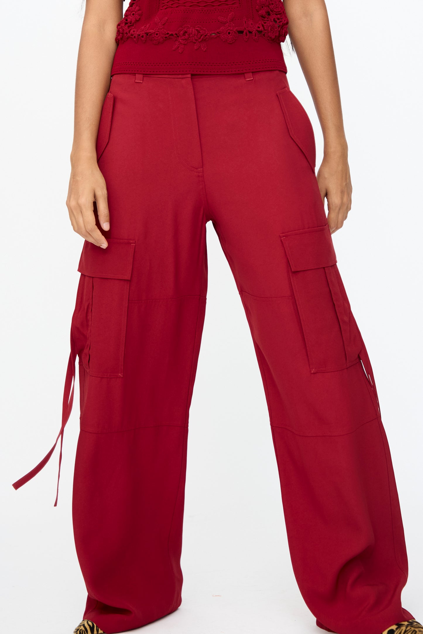 A person wearing the Ulla Johnson Pax Pant in Dahlia, a high-waisted, wide-leg cargo style with large side pockets and a matching red top in satin-backed crepe; shown from mid-torso to feet.