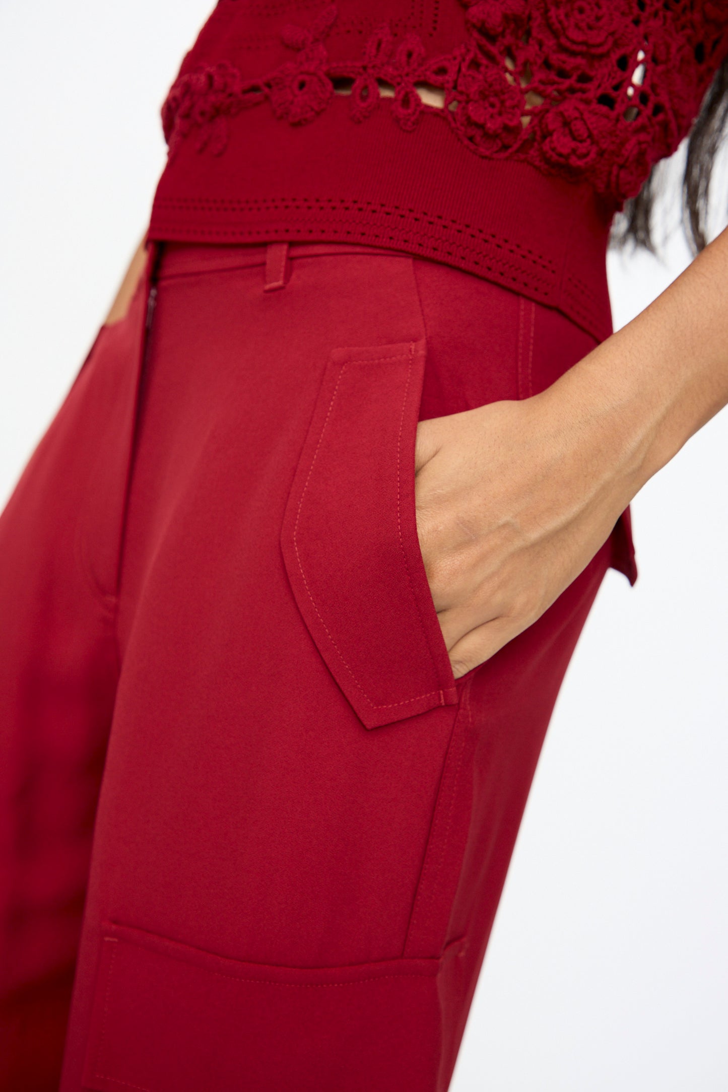 A person wearing the Ulla Johnson Pax Pant in Dahlia with one hand in the pocket, paired with a red lace top.