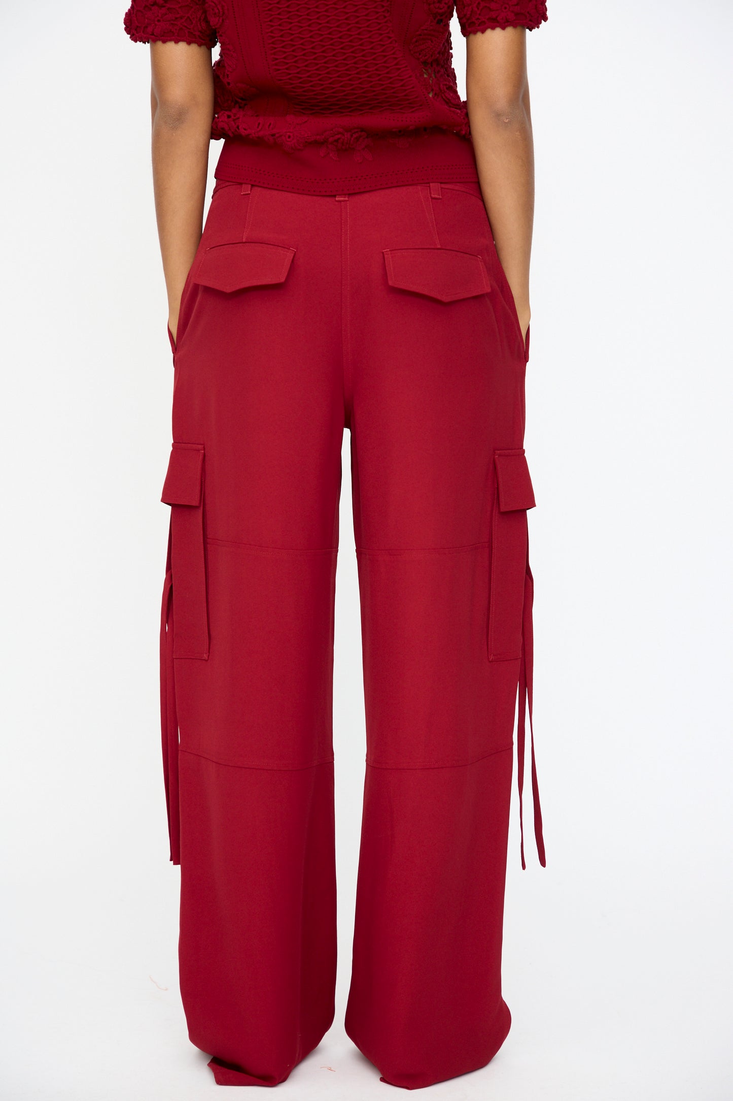 Model wears the Pax Pant in Dahlia by Ulla Johnson—a high-waisted, relaxed fit wide-leg cargo pant with pocket flaps and side straps—shown from the back against a plain white background.