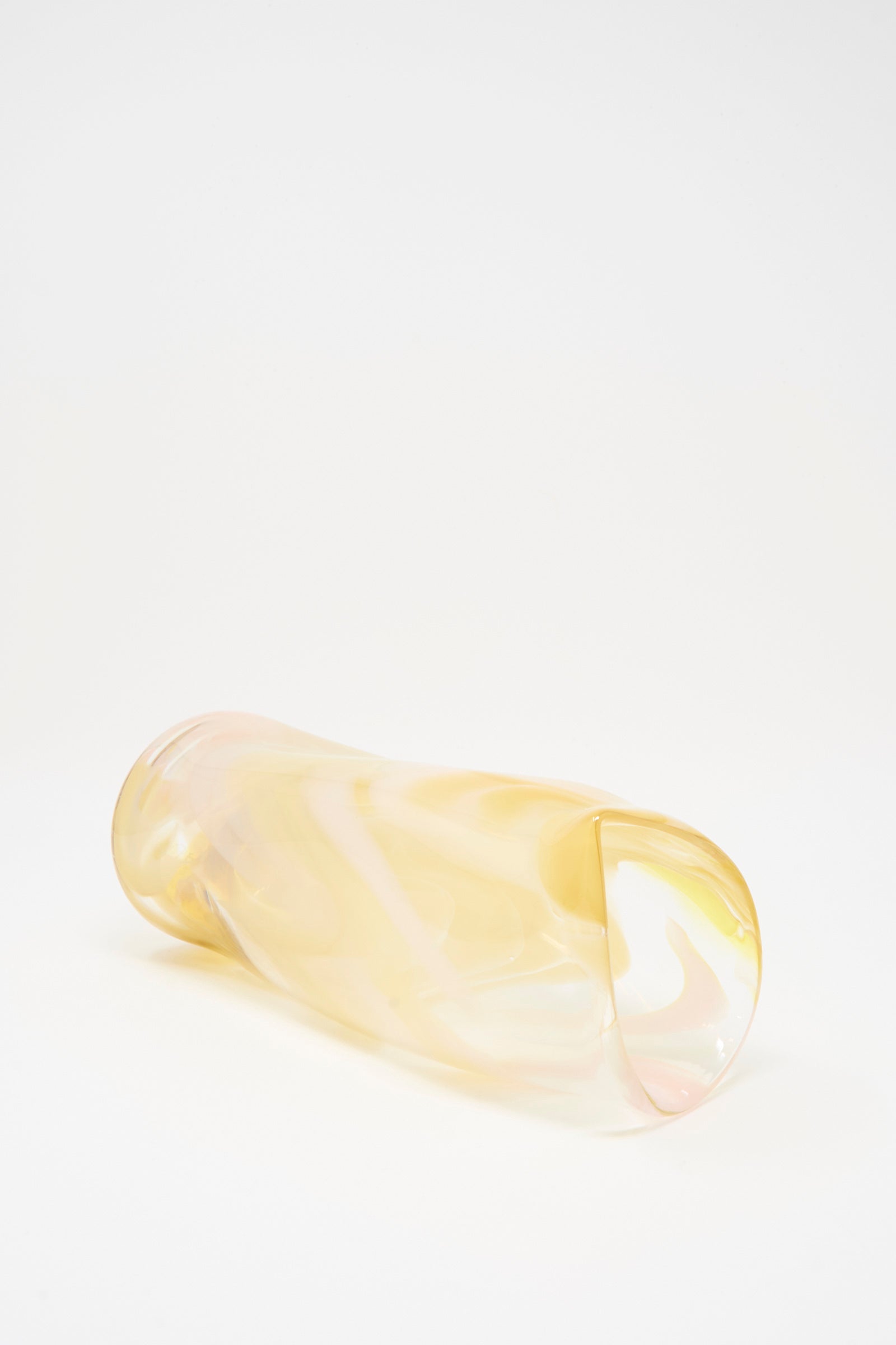 The Upstate Hand Blown Carafe in Frankie, made of translucent iridescent yellow glass, rests on its side against a plain white background.