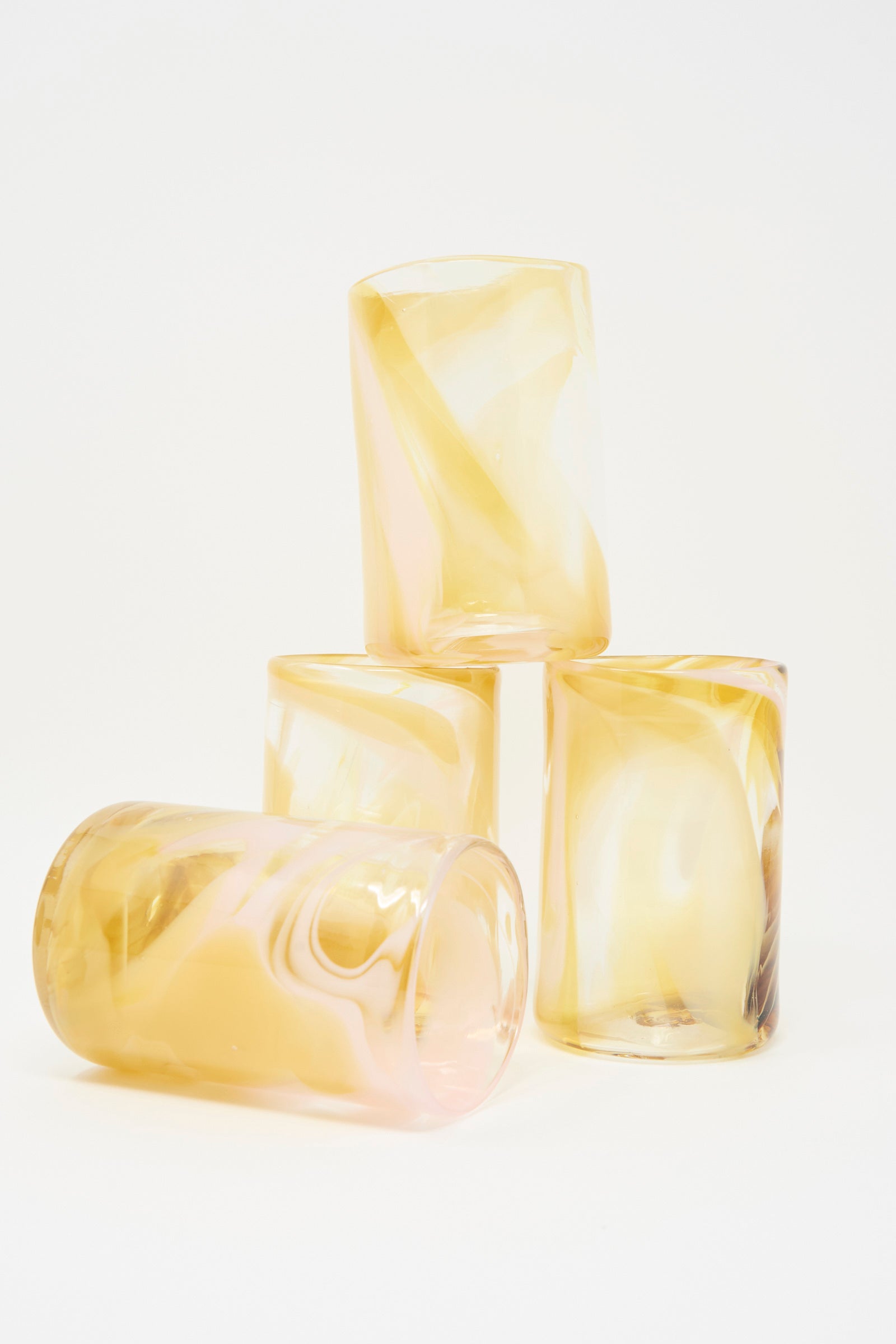 Four Upstate Hand Dyed Frankie Glass tumblers in yellow are artfully stacked against a plain white background.