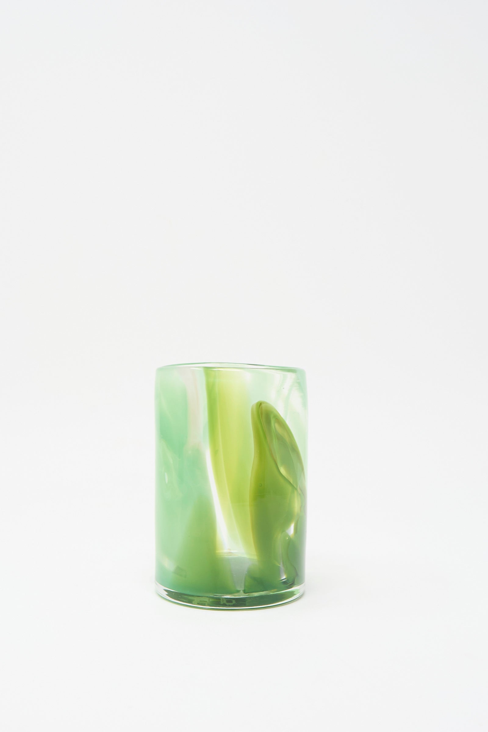 The Upstate Hand Dyed Moss Glass, a green hand-blown tumbler with marbled patterns, handmade in NYC, rests on a white surface against a plain white background.