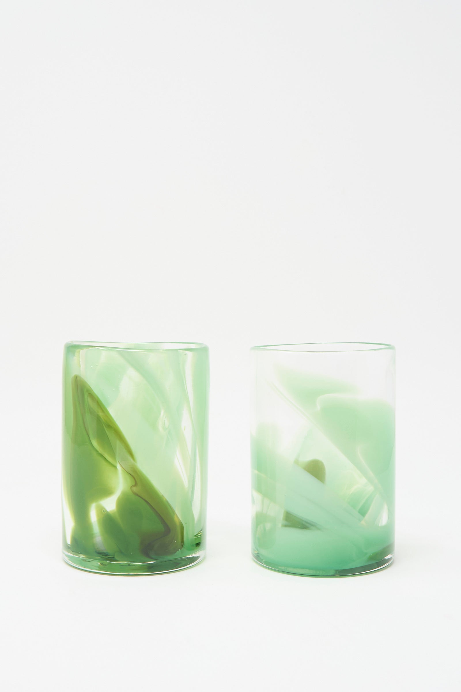 Two Upstate Hand Dyed Moss Glass tumblers, handmade in NYC and featuring abstract green swirls, are displayed side by side on a white background.