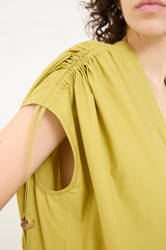 A close-up of a woman's arm in an oversized Veronique Leroy Cotton Poplin Gathered Dress in Matcha.