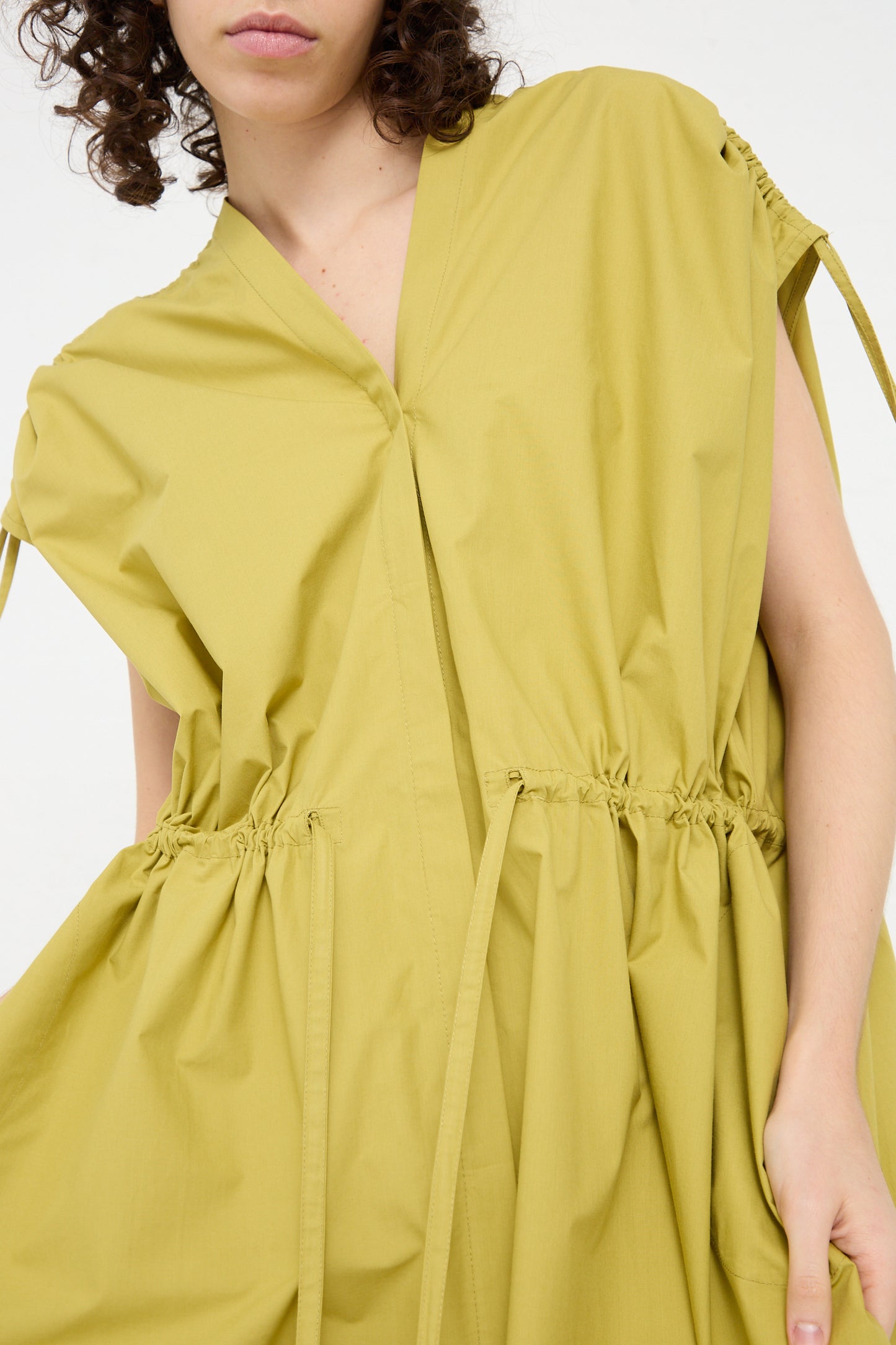 The model is wearing an oversized yellow Veronique Leroy cotton poplin dress with a ruffled sleeve.