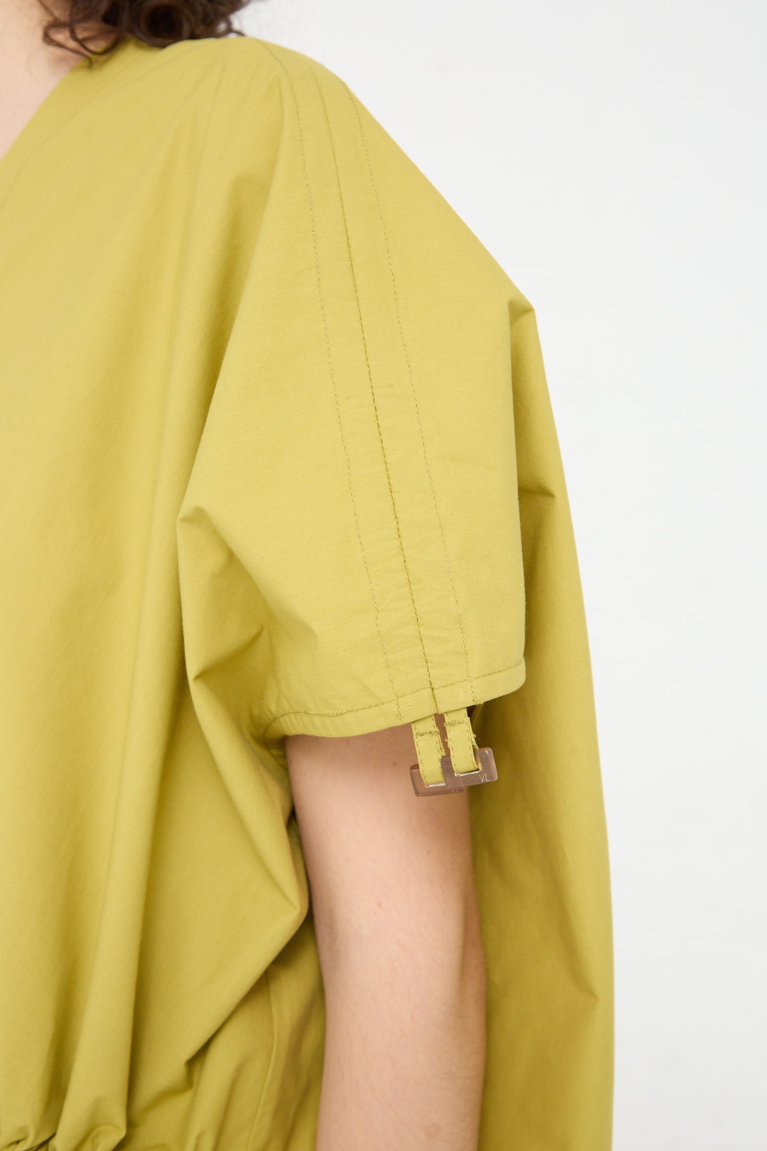 The side of a woman wearing an oversized yellow Veronique Leroy cotton poplin gathered dress in matcha.