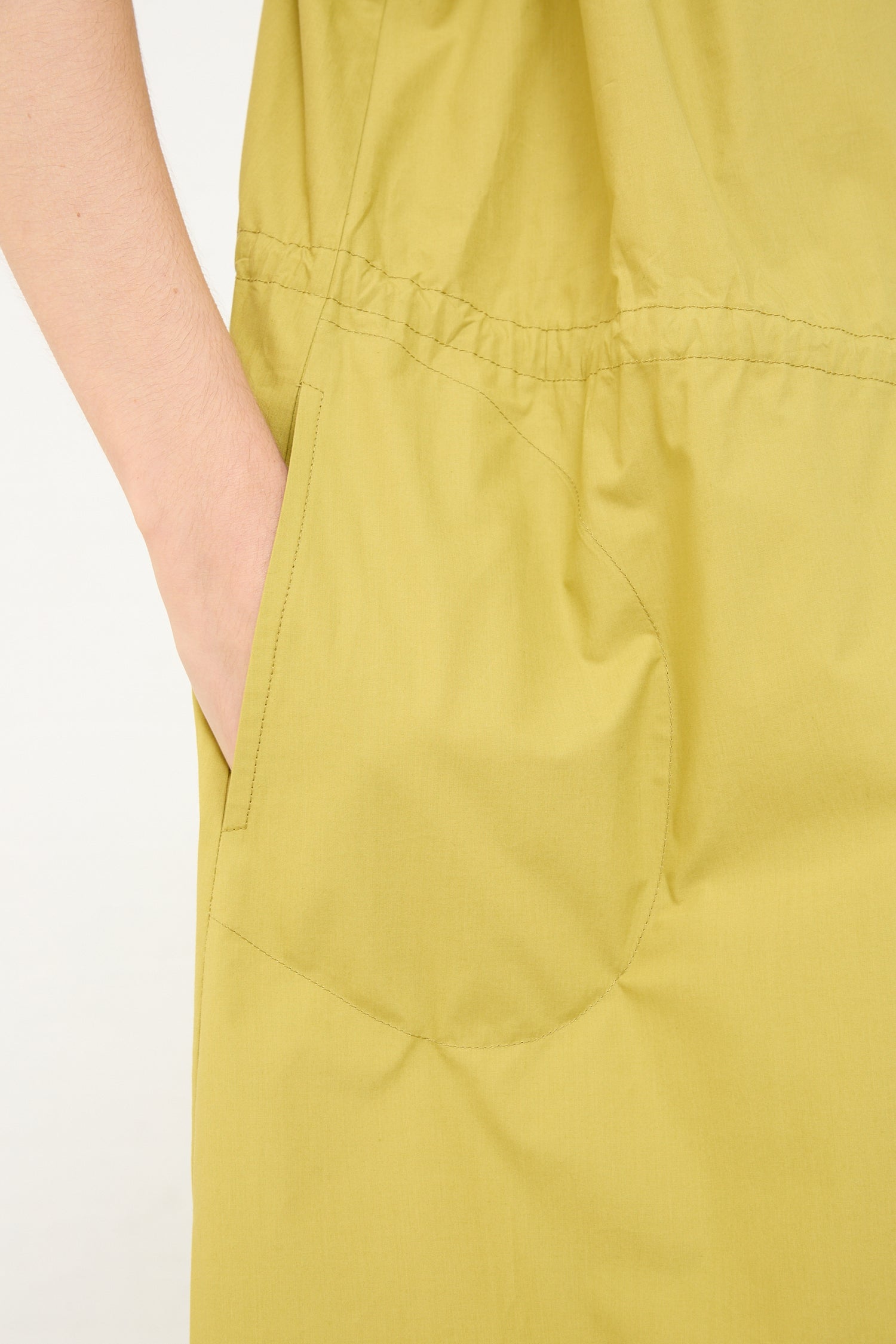 A woman wearing an oversized yellow Veronique Leroy Cotton Poplin Gathered Dress in Matcha with pockets. Up close view.