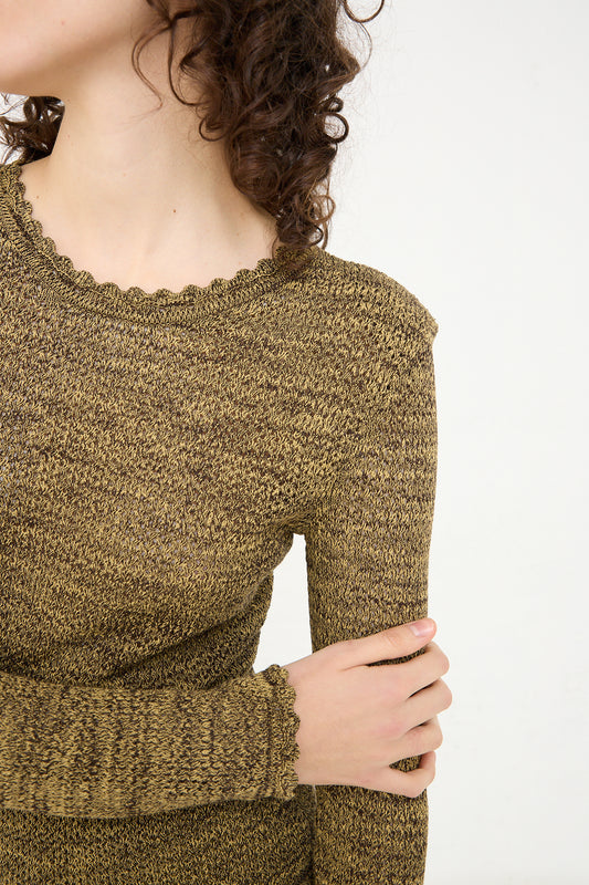 A woman with curly hair is posing for a photo in a Veronique Leroy Long Sleeve Knit Top in Pepper.