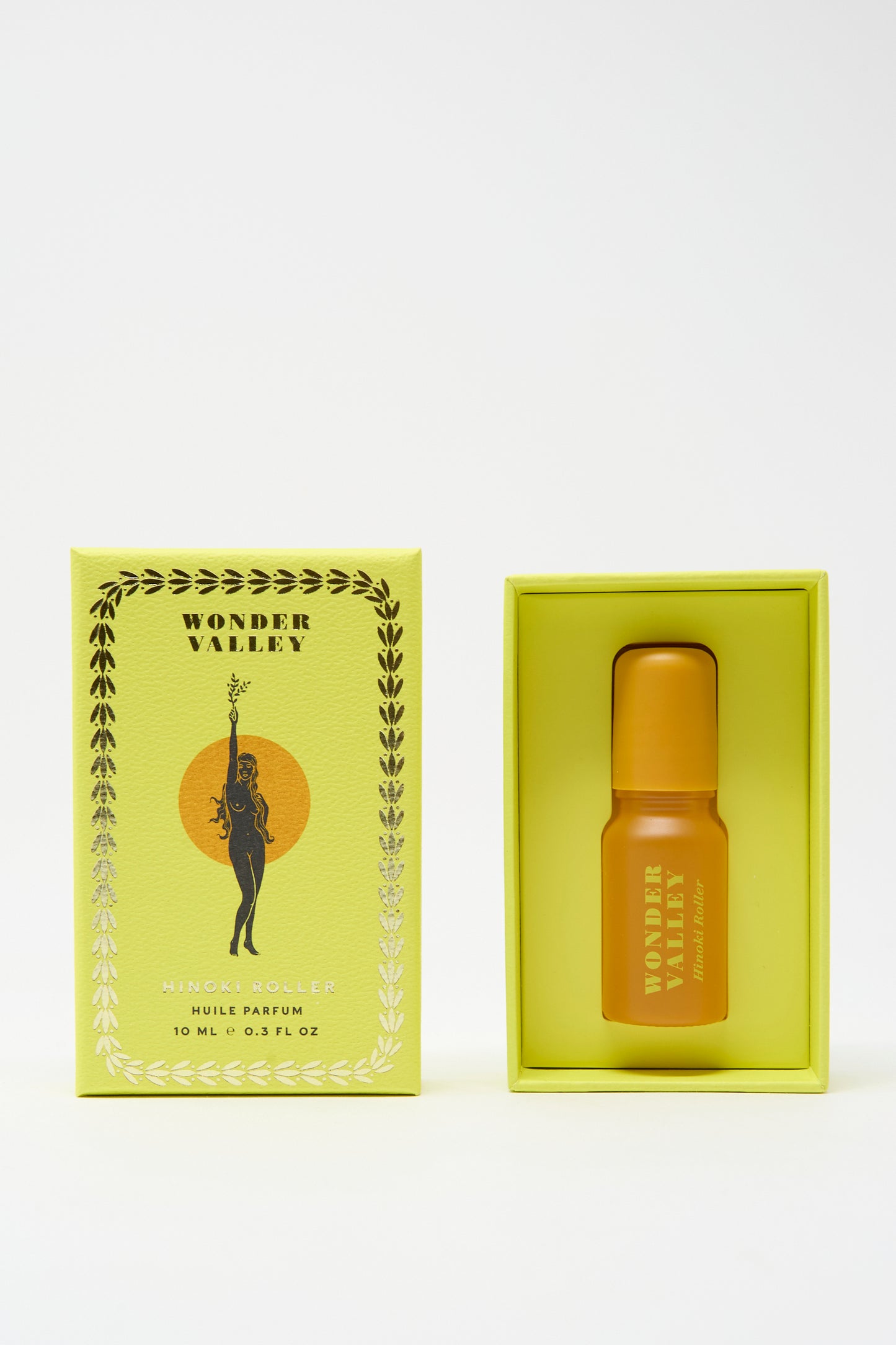 A yellow box labeled "Wonder Valley" with floral accents holds the Hinoki Roller, a small yellow bottle of essential oil-based perfume—perfect as a portable scent—shown next to its packaging.