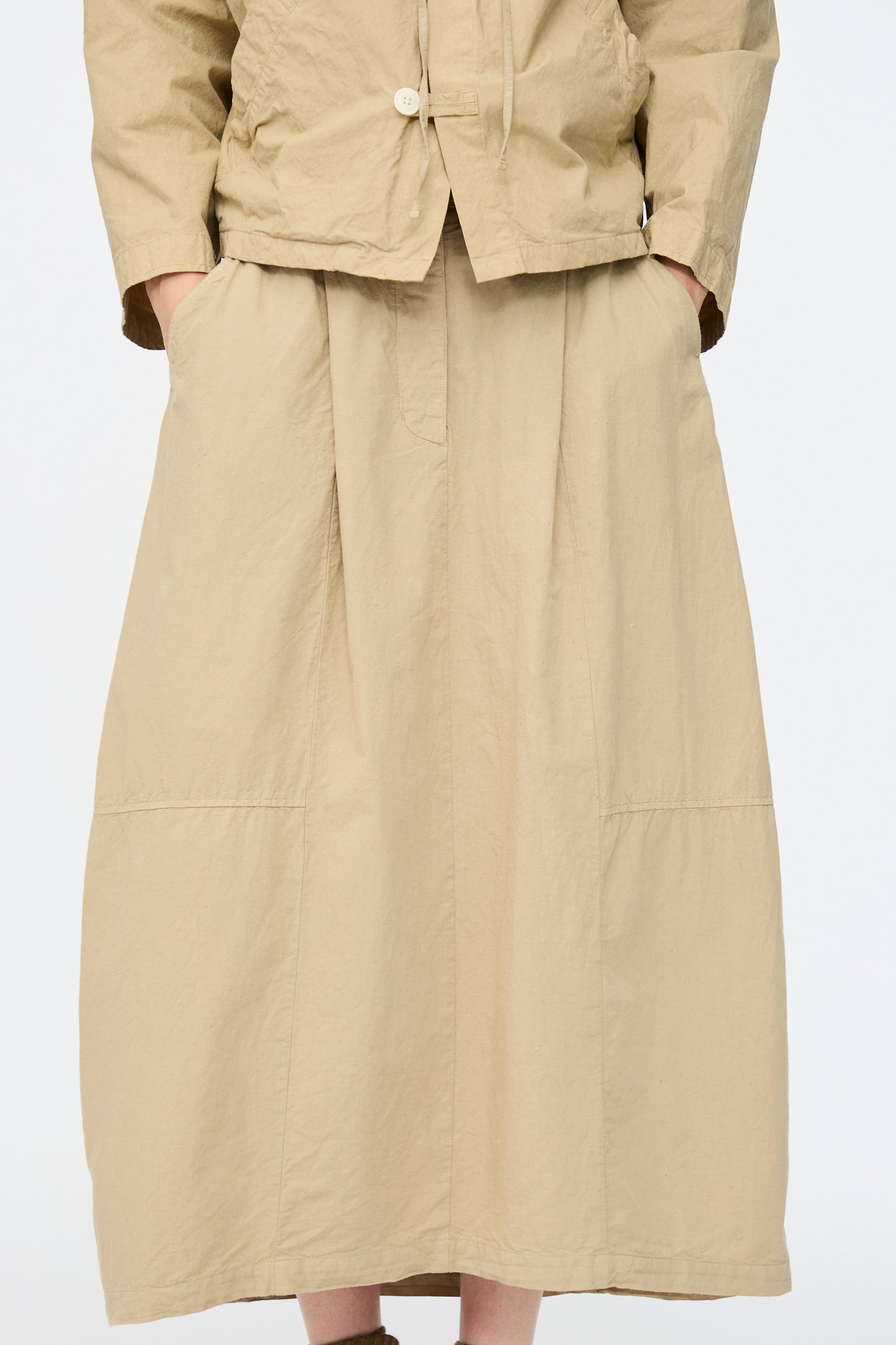Model wears the nest Robe Cotton Linen Dungaree Balloon Skirt in Beige with a matching relaxed fit jacket, hands in pockets, standing against a plain white background.