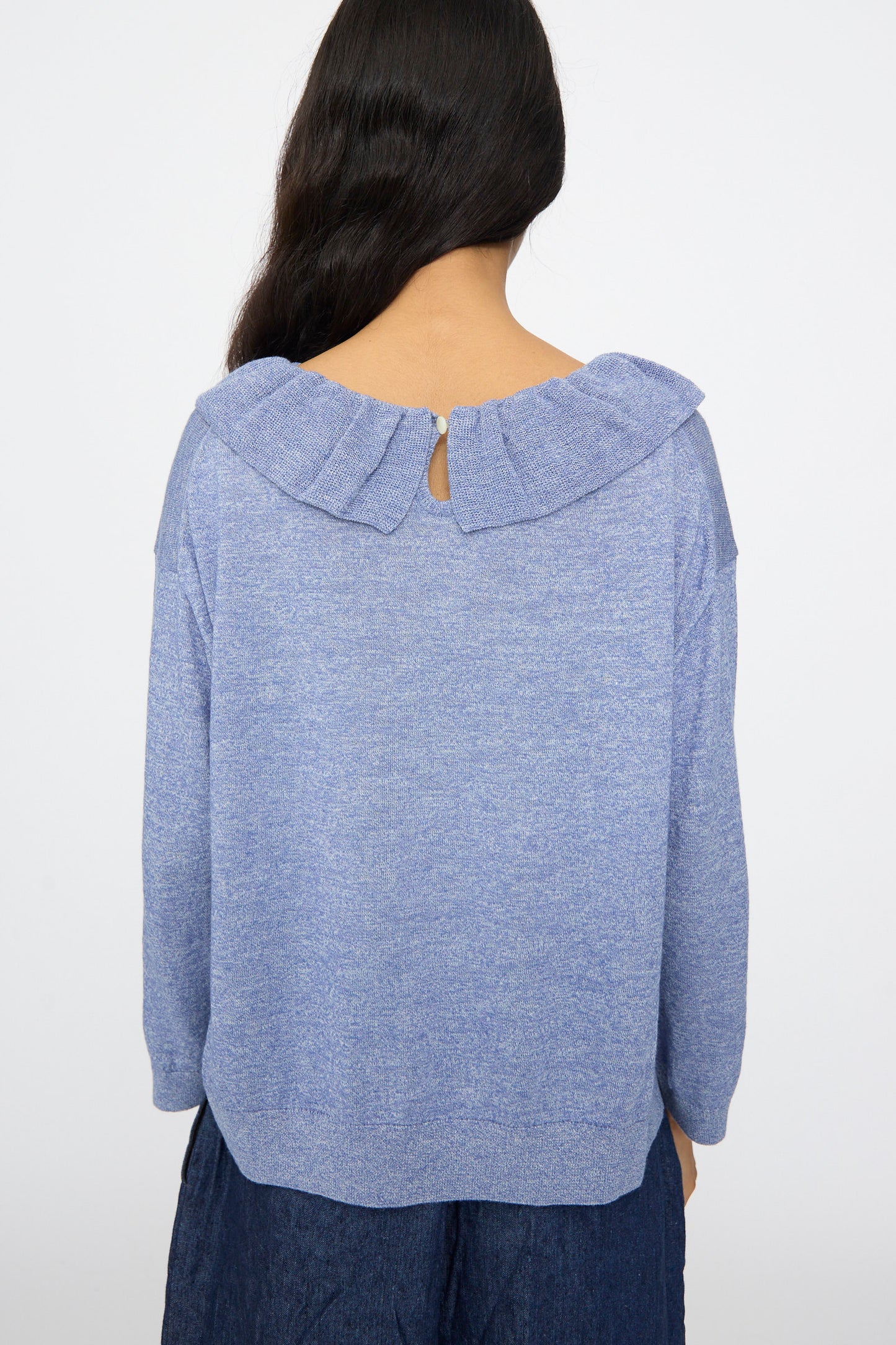 A person with long dark hair is seen from the back wearing the nest Robe Ruffle Collar Knit Pullover in Blue, set against a plain white background.