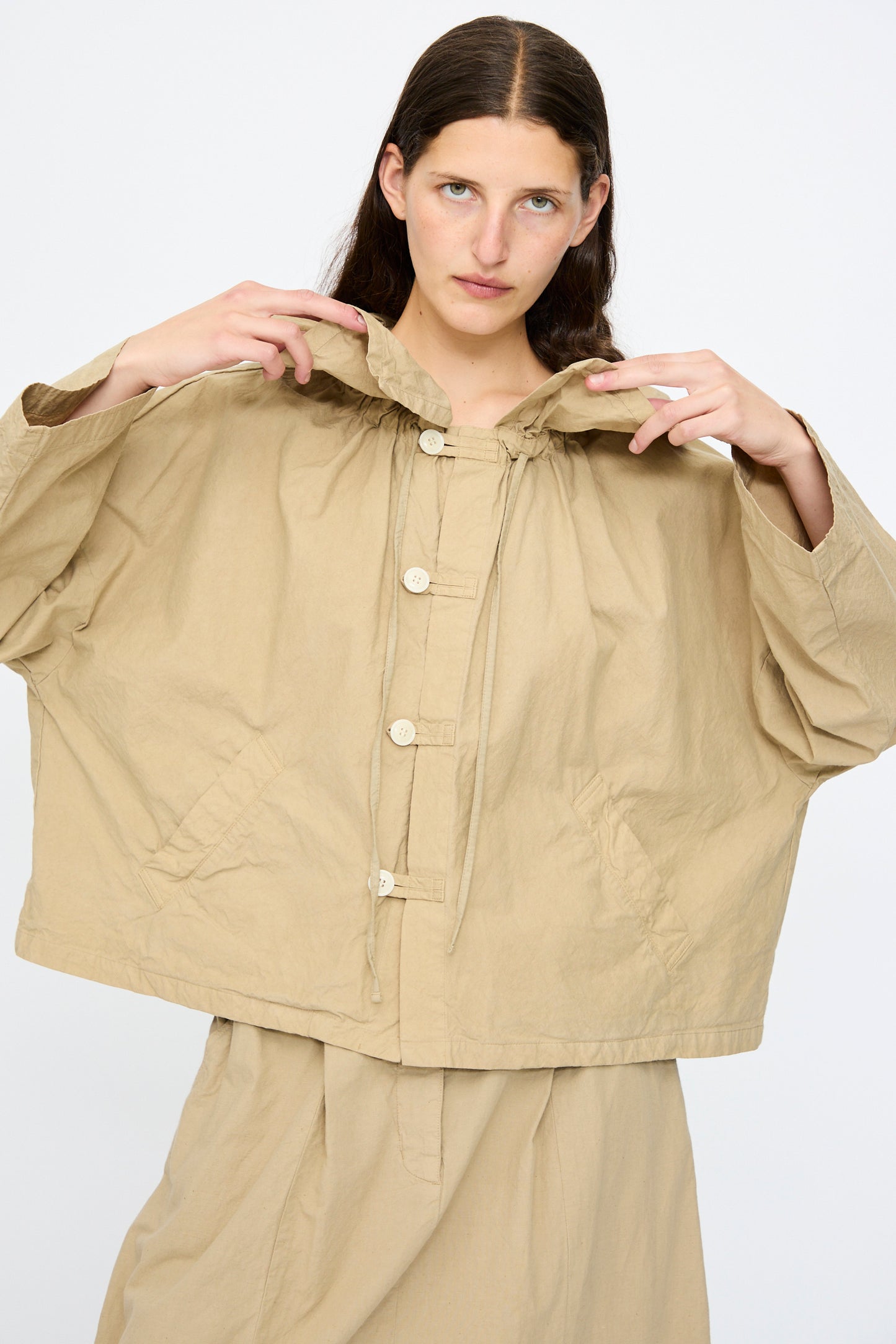 A person with long brown hair wears the nest Robe Super Water-Repellent Supima Cotton Leaf Collar Jacket in beige, styled with a matching skirt, posing against a plain white background.