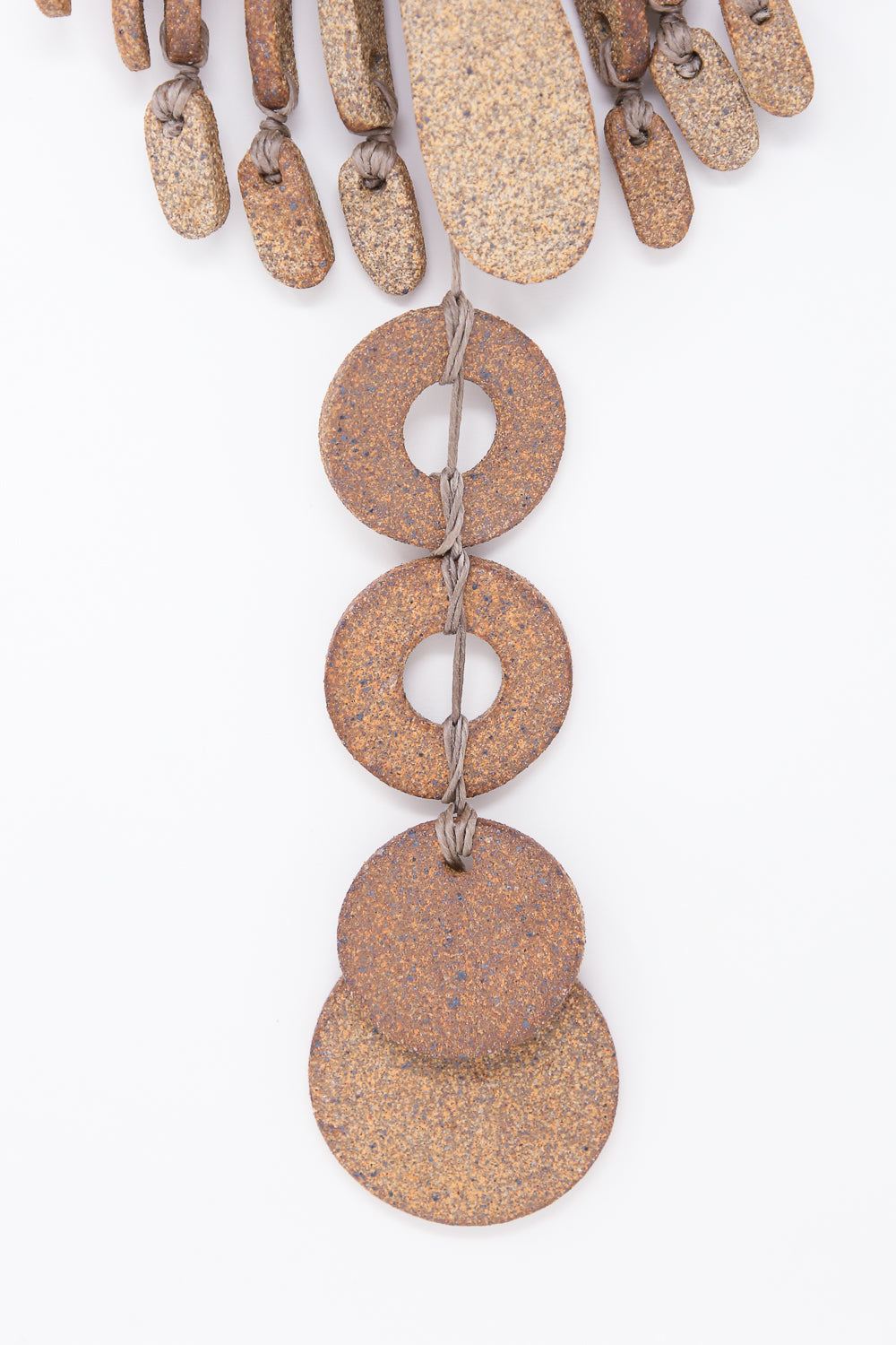 A close-up of the Heather Levine Teardrop and Circle Wall Hanging in Mixed Brown, a handmade ceramic piece featuring round and oval-shaped textured stones connected with string, set against a white background.