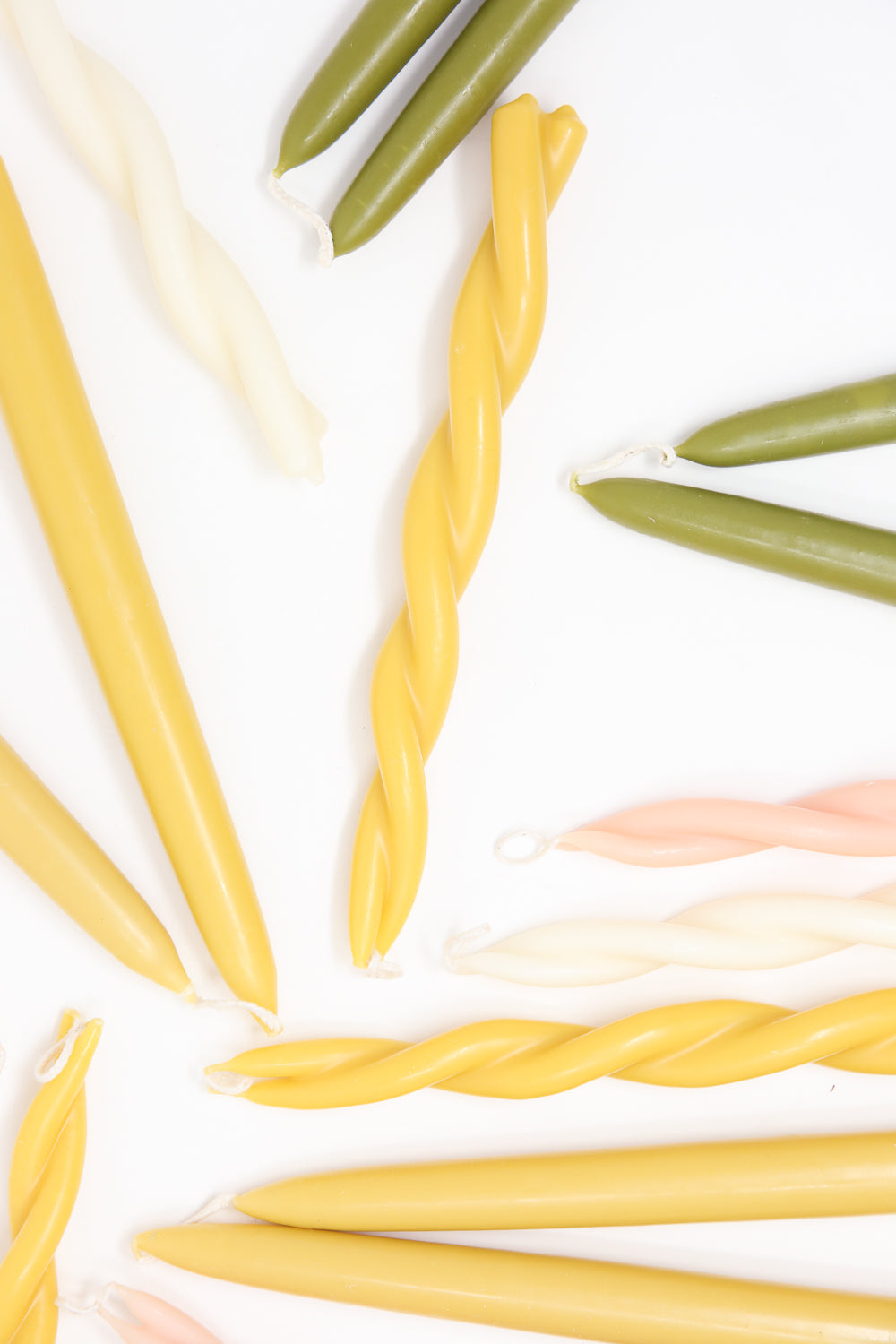 Assorted colorful Hand Twisted Beeswax Candles in Natural arranged neatly on a white background by Wax Atelier.